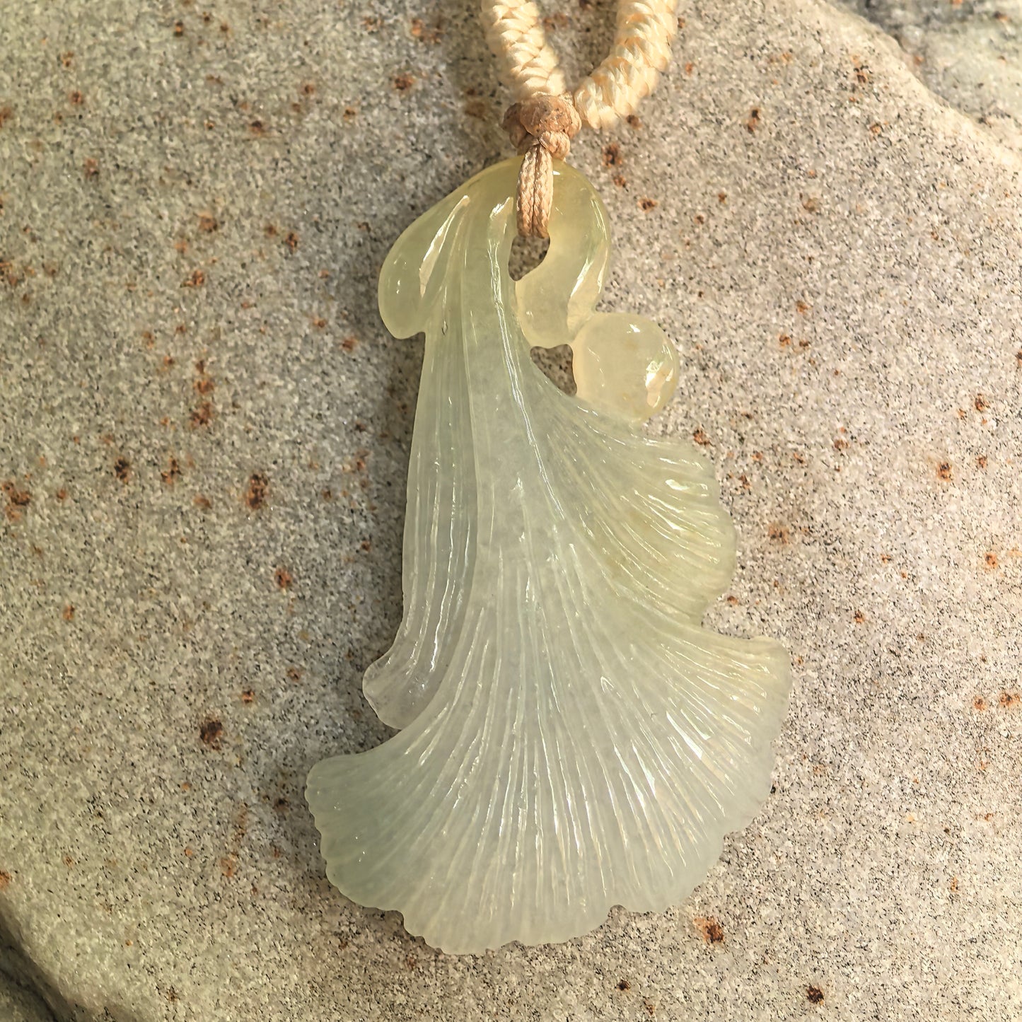 Close-up of carved jadeite ginkgo leaf pendant showing clean color, yellow-brown accent, and soft translucency.