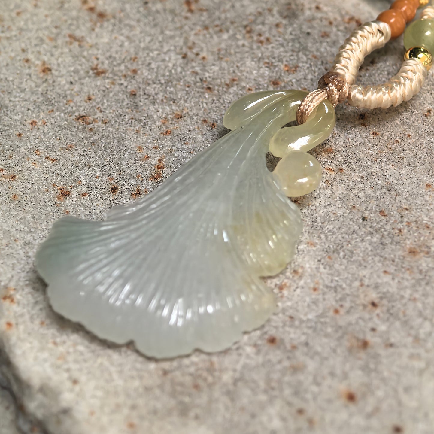 Side view of light green ginkgo leaf jadeite pendant showing curved shape and detailed leaf texture.
