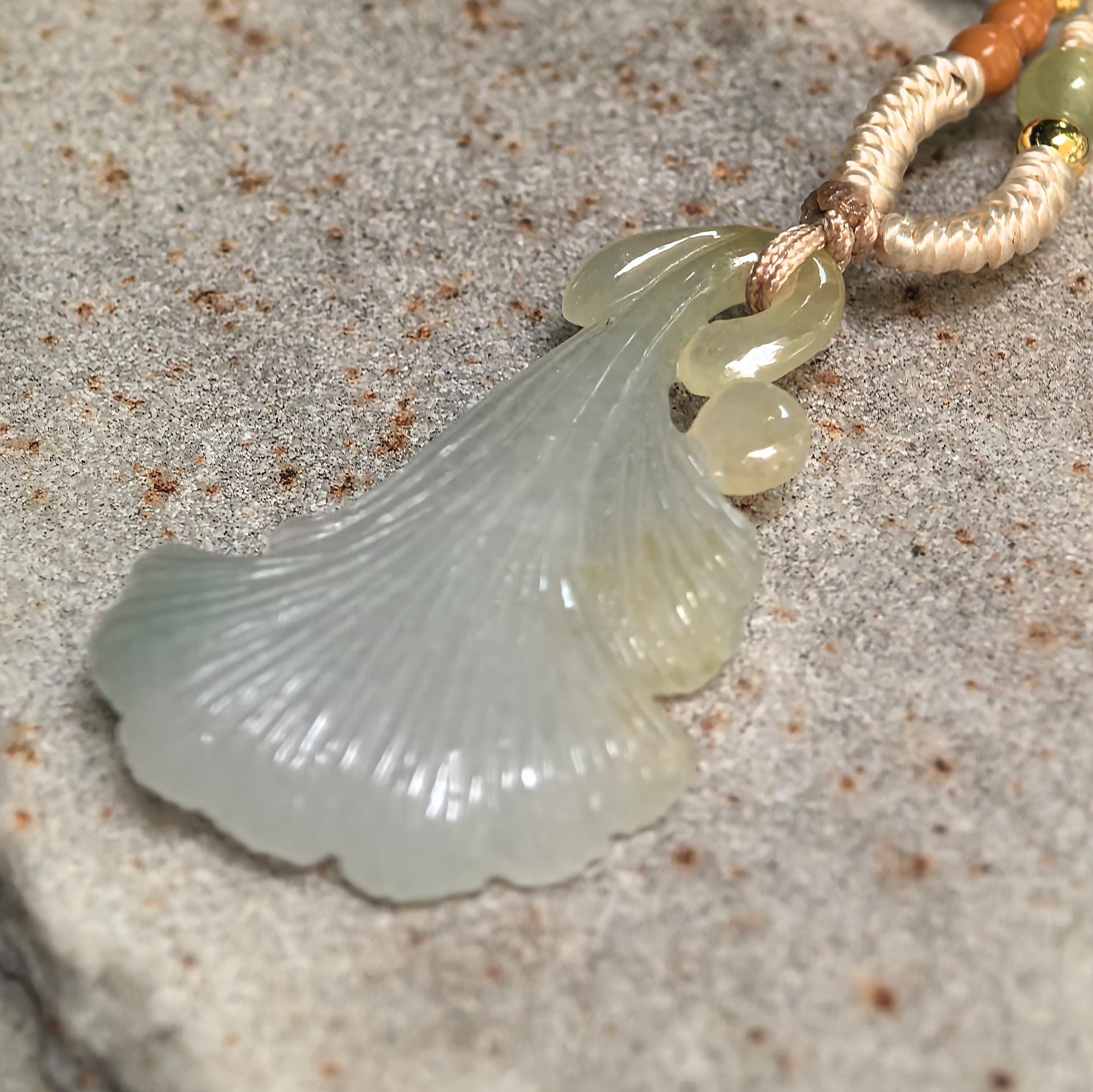 Side view of light green ginkgo leaf jadeite pendant showing curved shape and detailed leaf texture.