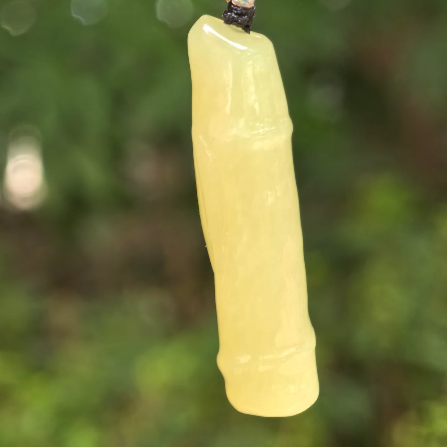 Natural Hetian jade yellow bamboo section pendant hanging against a soft green background.