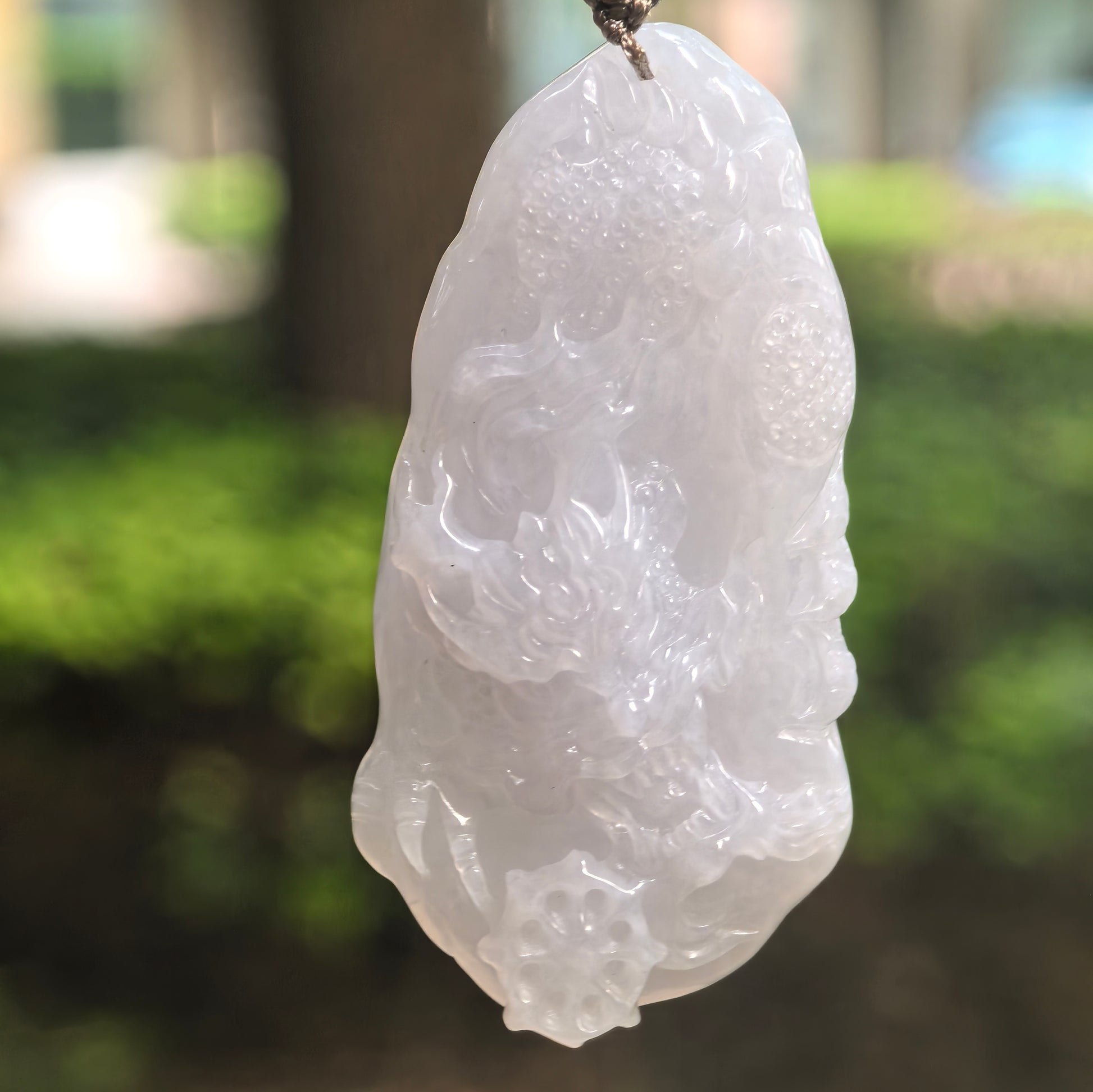 Natural Grade-A glutinous white jadeite dragon pendant hanging on cord.