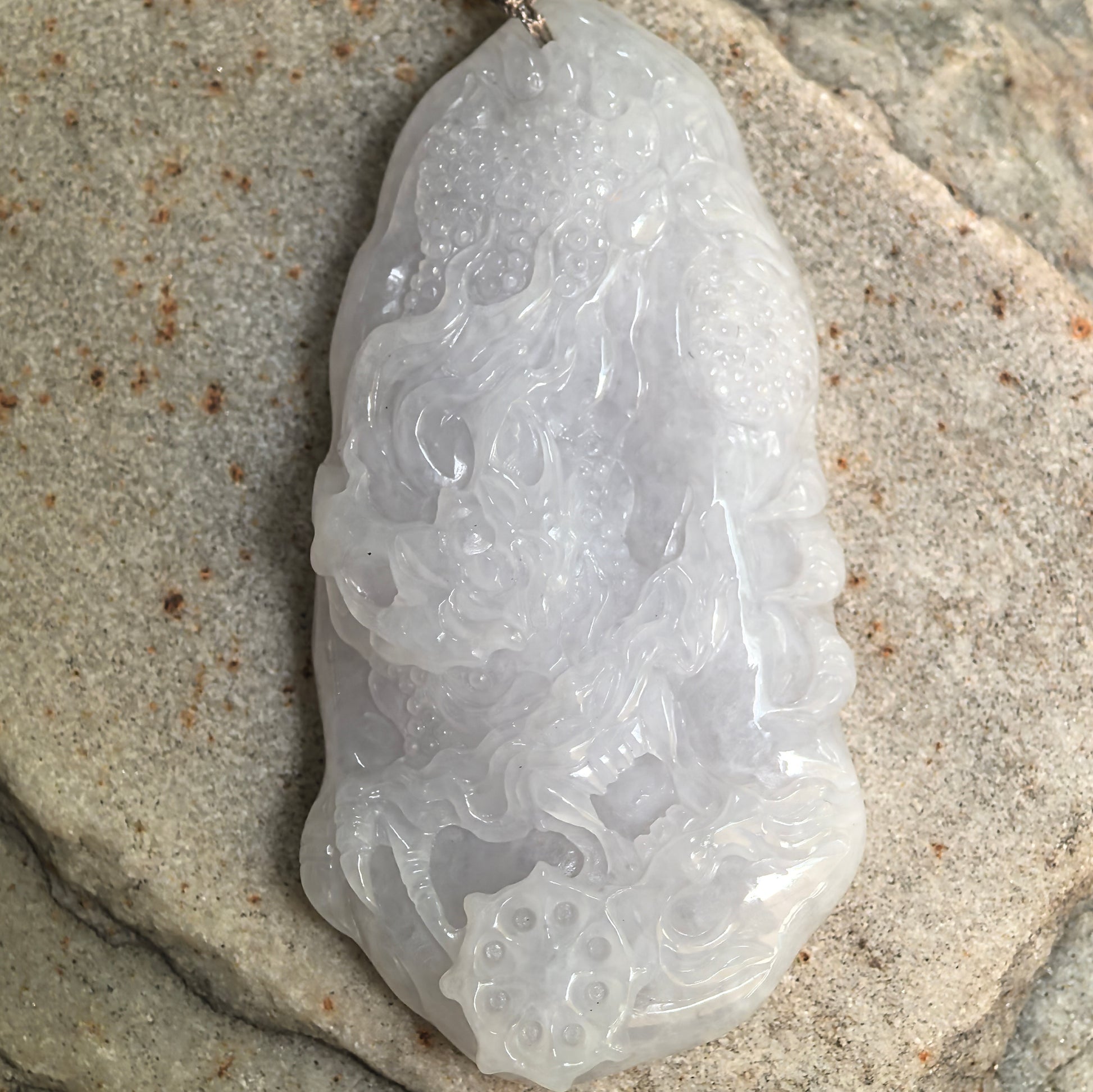 Close-up of carved white jadeite dragon pendant showing smooth polish and soft translucency.