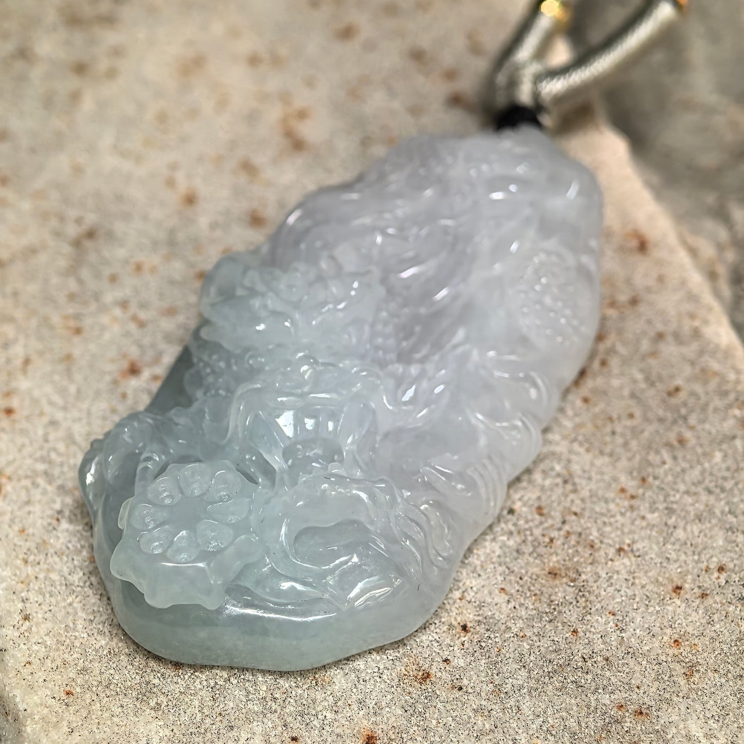 Side view of pale green jadeite dragon pendant showing approximately 10.5 mm thickness.