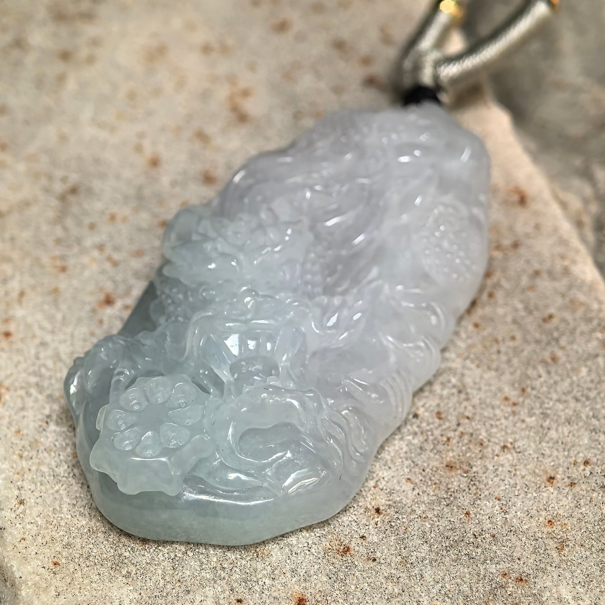 Side view of pale green jadeite dragon pendant showing approximately 10.5 mm thickness.
