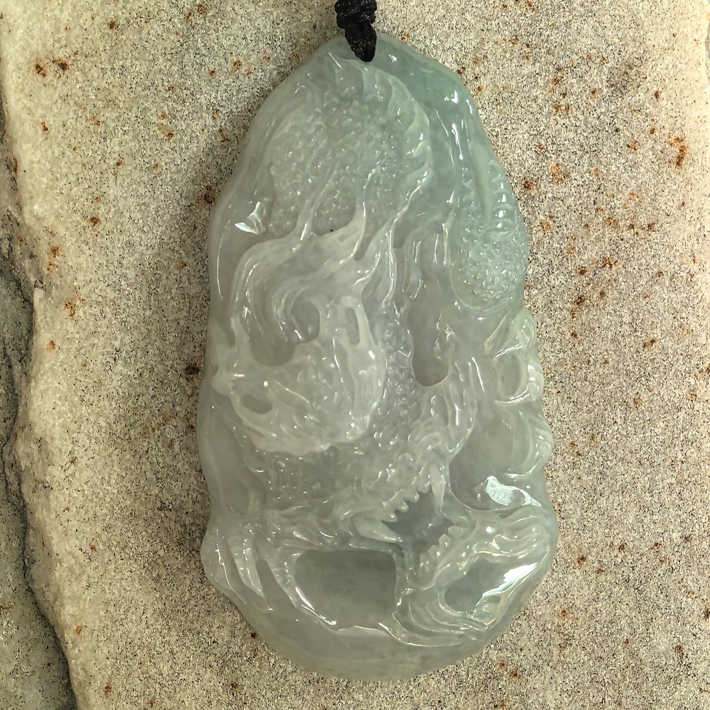 Close-up of carved jadeite dragon pendant showing smooth polish and soft translucency.