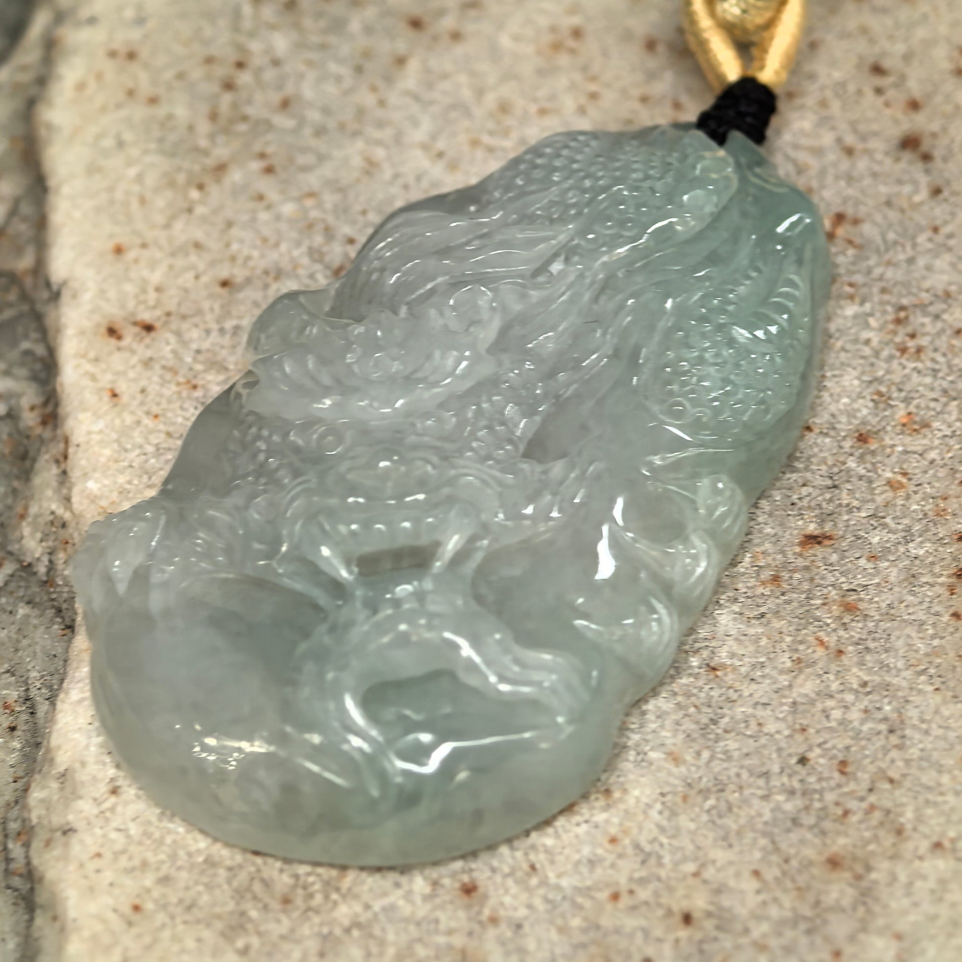 Side view of pale green jadeite dragon pendant showing approximately 10 mm thickness.