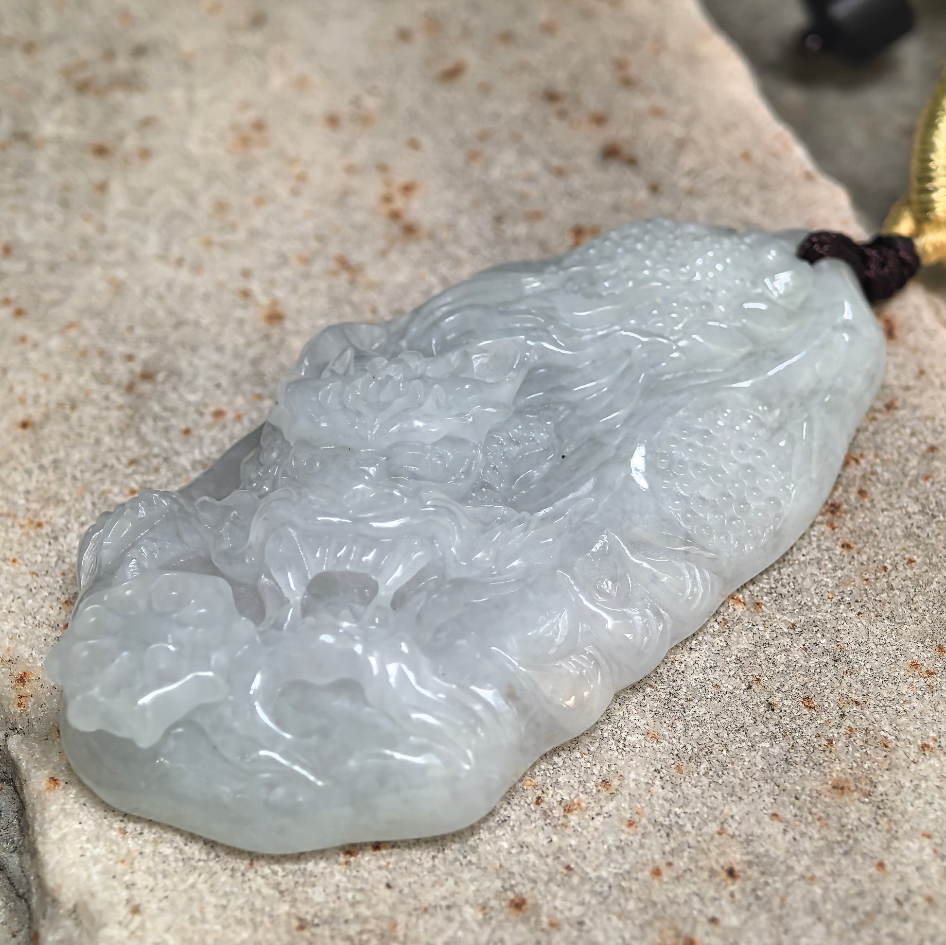 Side view of pale green jadeite dragon pendant showing approximately 10.5 mm thickness.