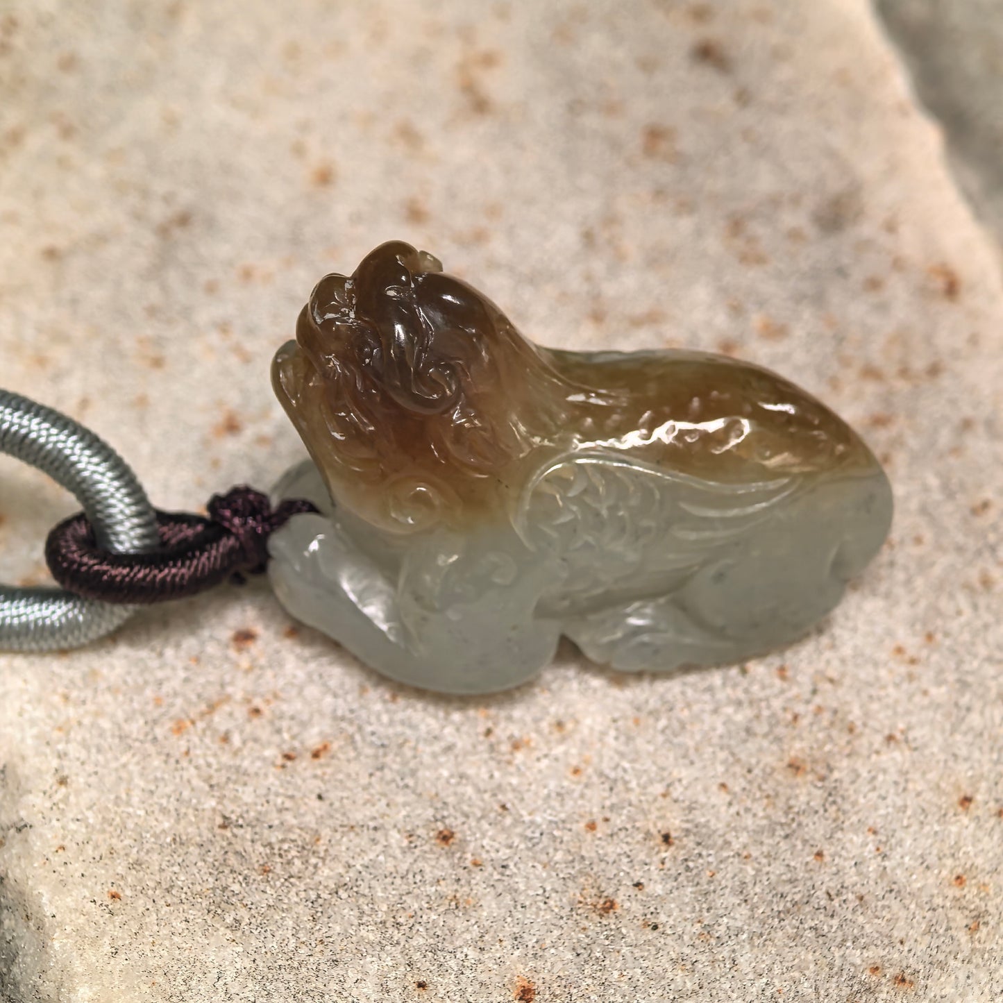 Close-up of 3D carved Hetian jade Pixiu pendant showing rounded body and glossy oily luster.