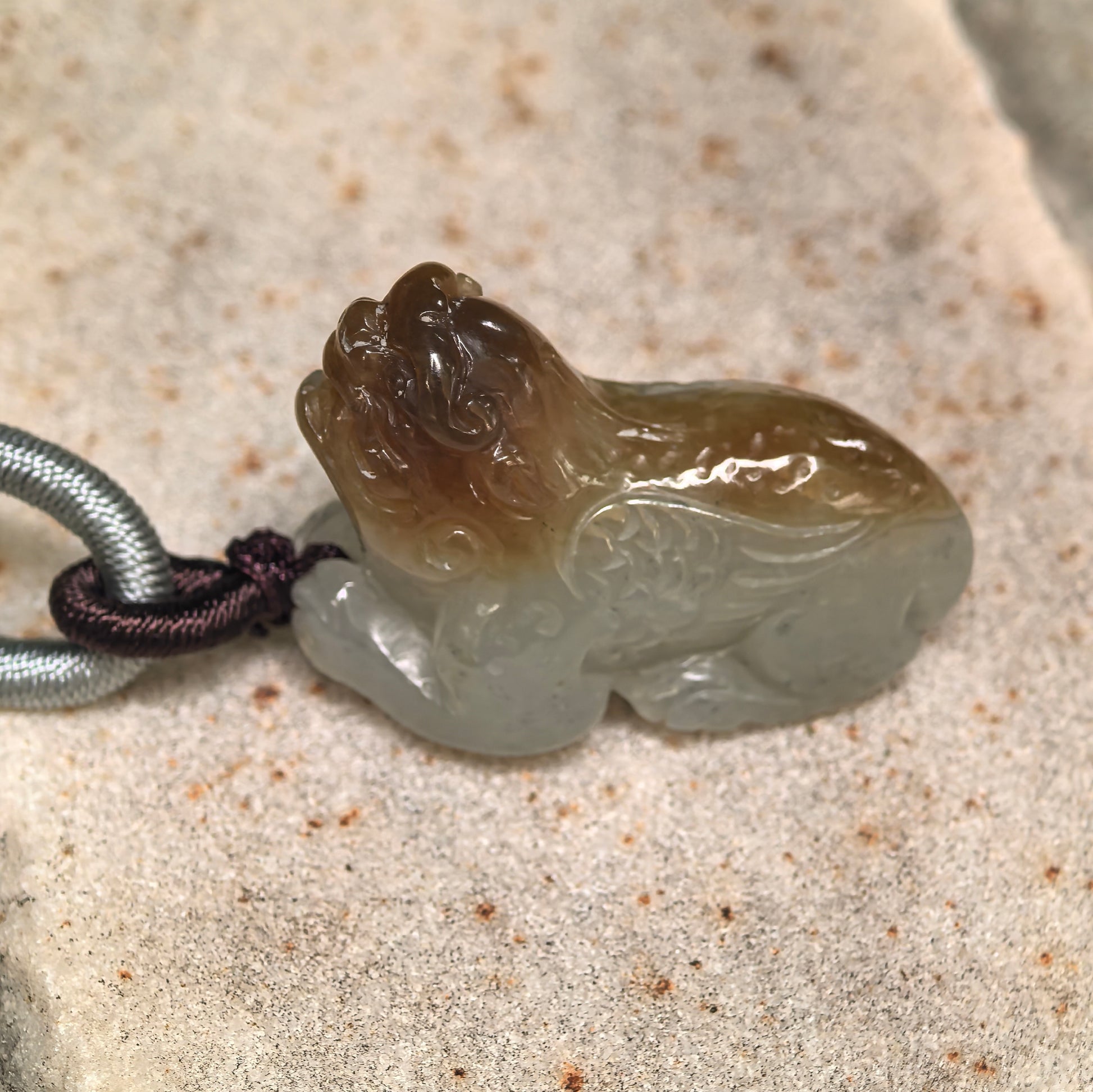 Close-up of 3D carved Hetian jade Pixiu pendant showing rounded body and glossy oily luster.