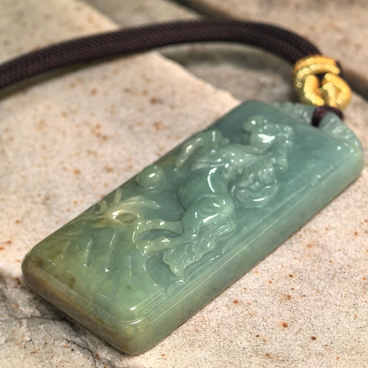 Side view of glutinous deep green jadeite horse pendant showing solid thickness and polished edges.