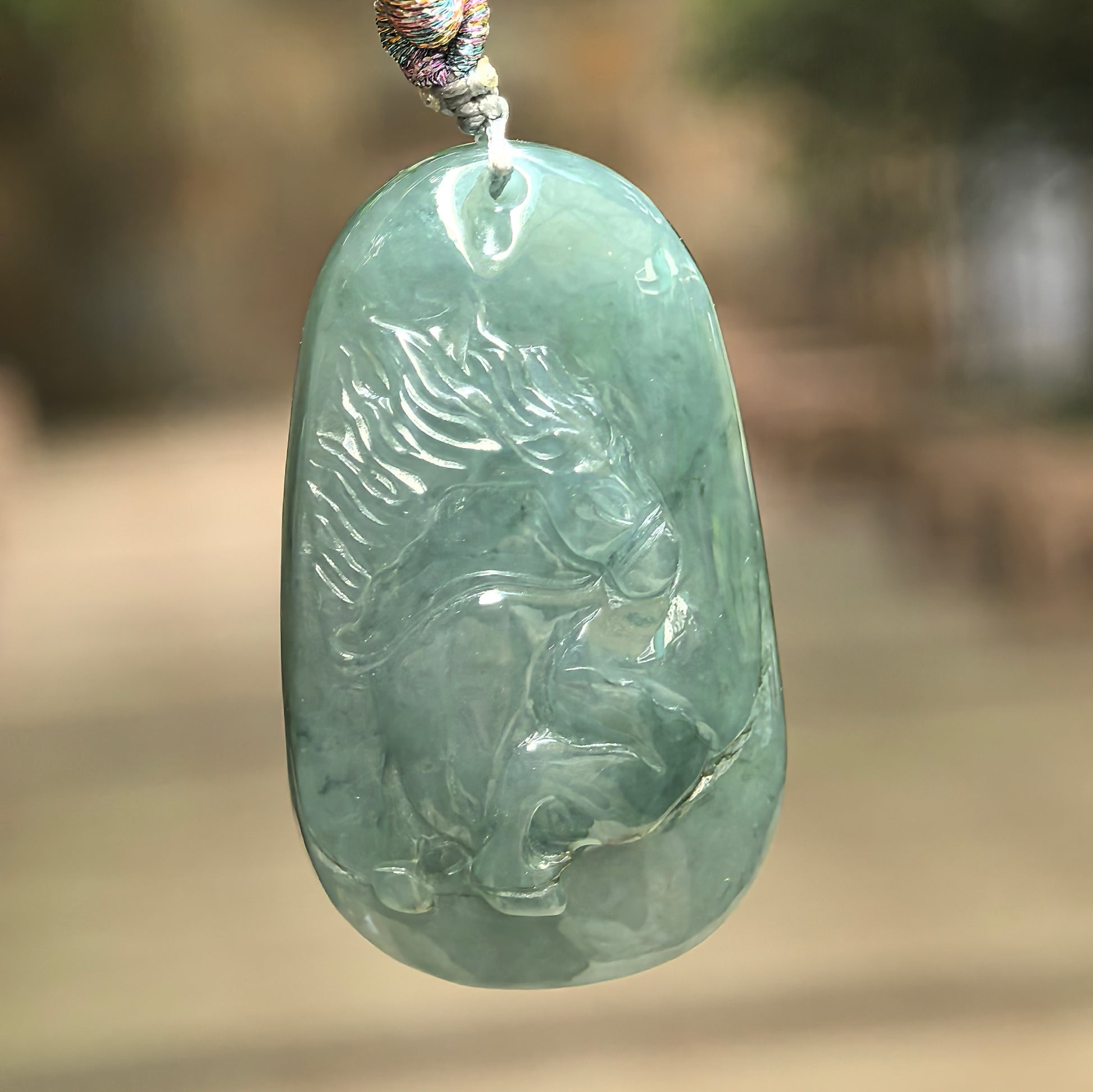 Natural Grade-A glutinous deep green jadeite horse pendant hanging on cord.