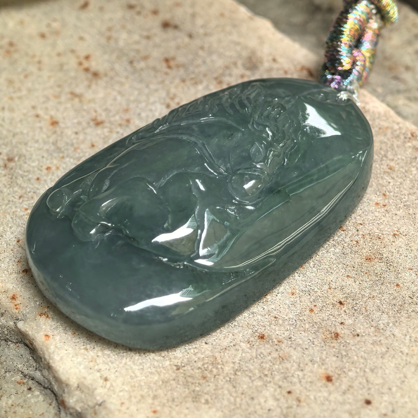 Side view of deep green jadeite horse pendant showing approximately 11.6 mm thickness.