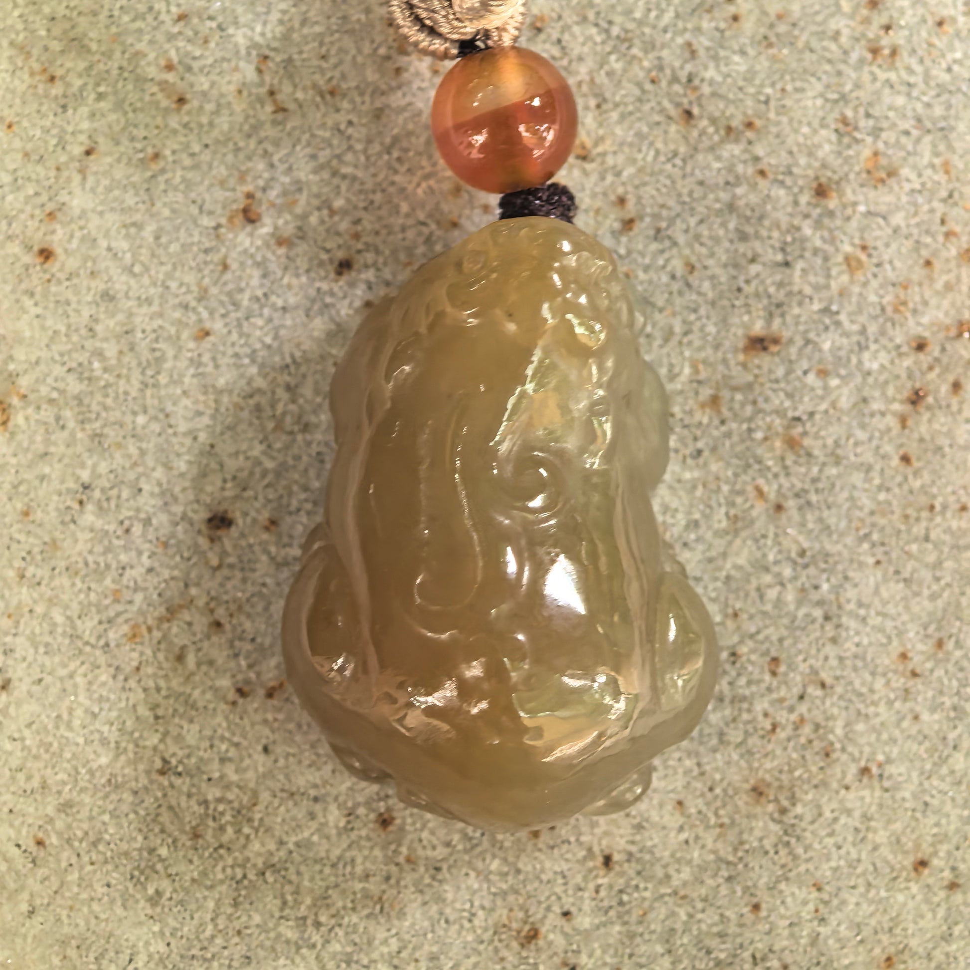 Close-up of natural Hetian jade Pixiu carving showing glossy polish and warm brown tone.