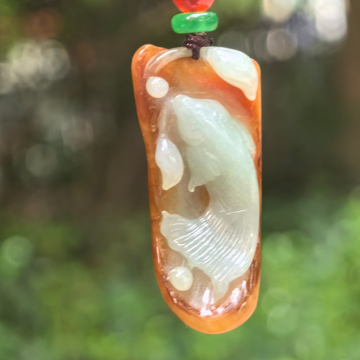 Natural Grade-A glutinous yellow and pale green jadeite fish pendant hanging on cord.