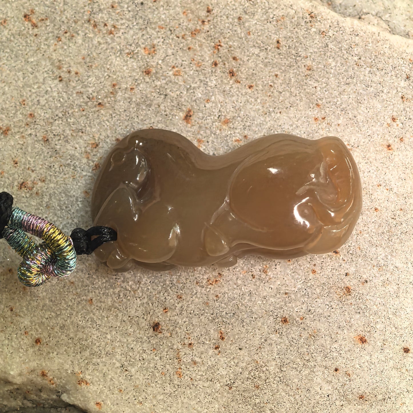 Close-up of natural Hetian jade horse carving showing glossy polish and warm brown tone.