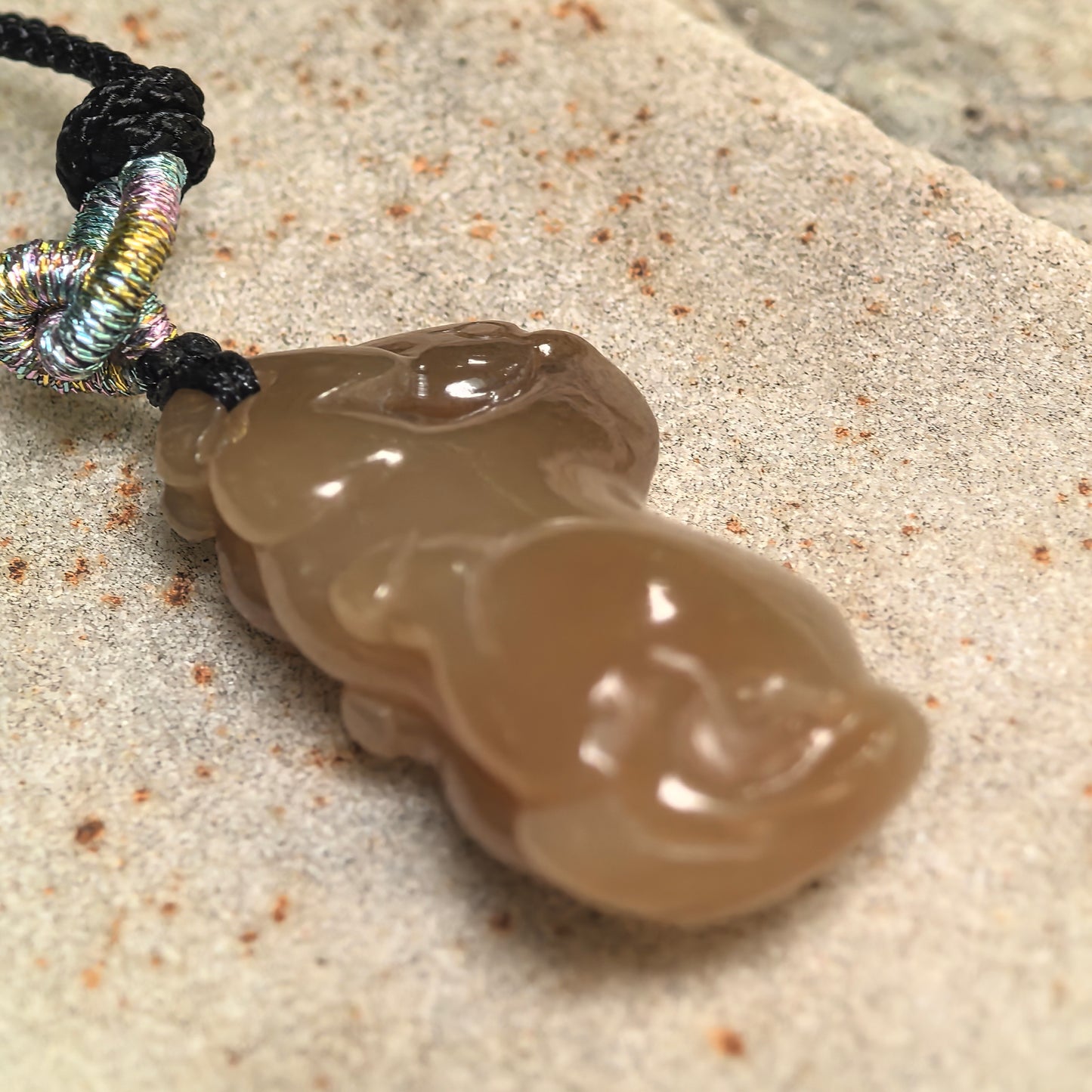 Side view of 3D carved Hetian jade horse pendant showing sculptural thickness and smooth curves.