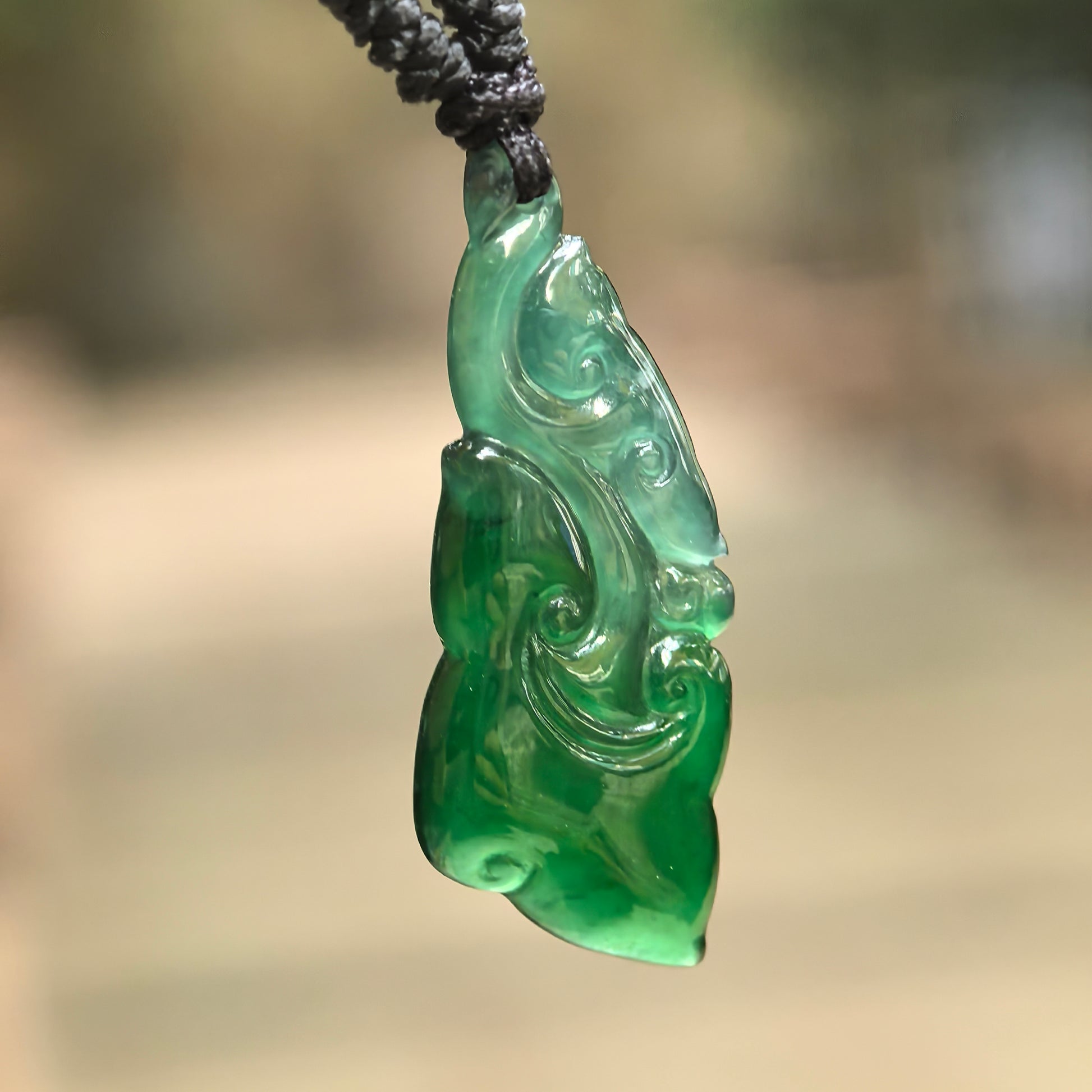 Natural Grade-A glutinous-icy dark green Guatemalan jadeite Ruyi pendant hanging on black cord.
