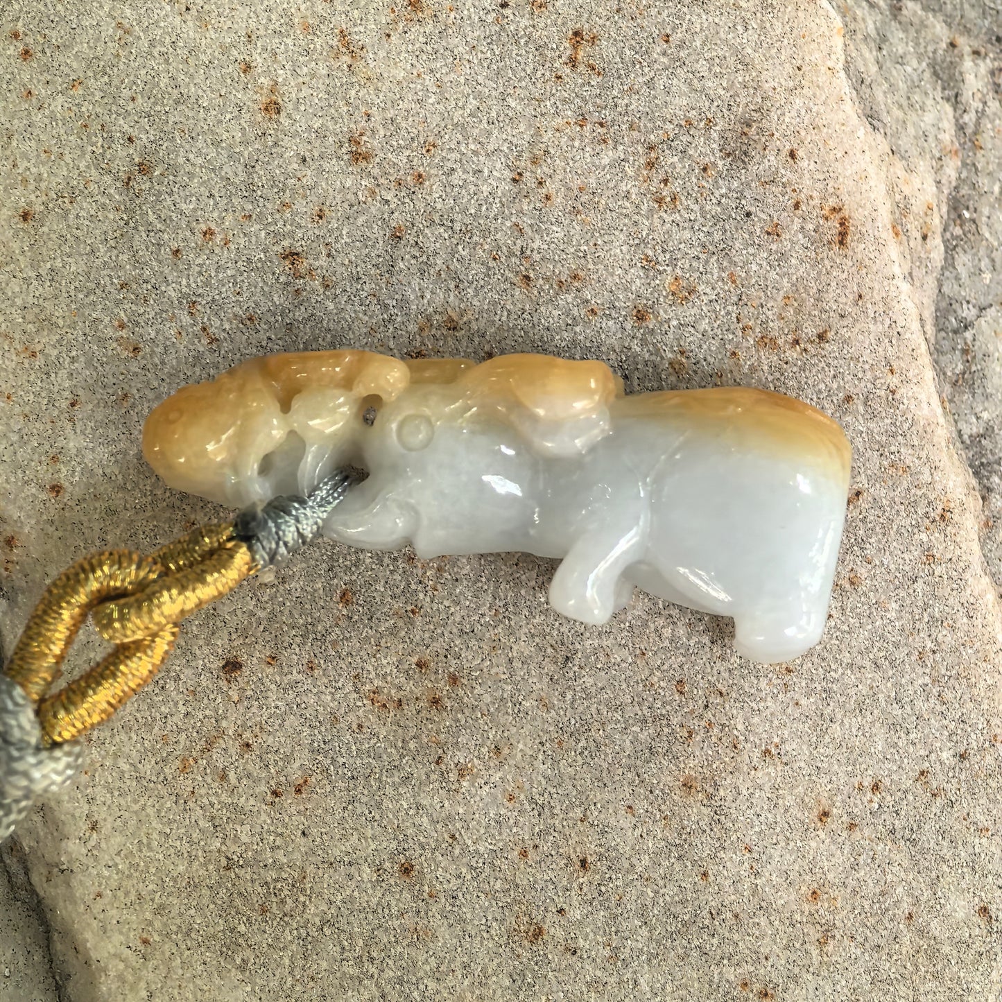 Side view of three-dimensional monkey-on-elephant jadeite pendant showing white base and yellow skin color.