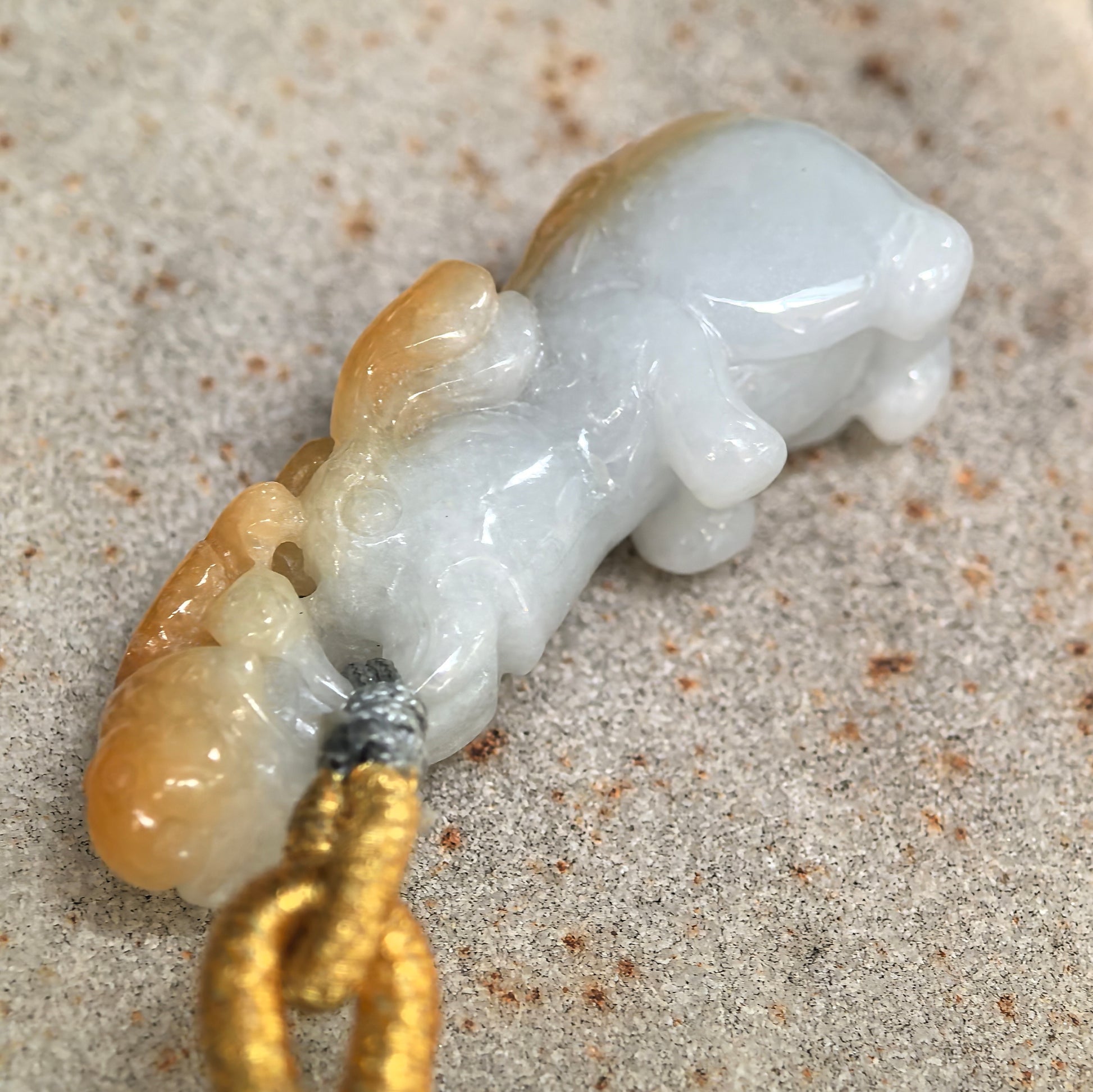 Close-up of natural jadeite elephant pendant showing glossy polish, rounded carving, and auspicious monkey motif.