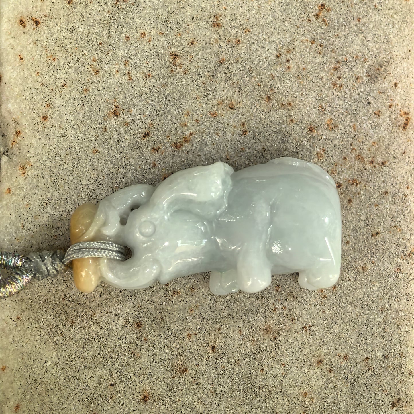 Side view of three-dimensional jadeite elephant pendant showing rounded body and raised trunk.