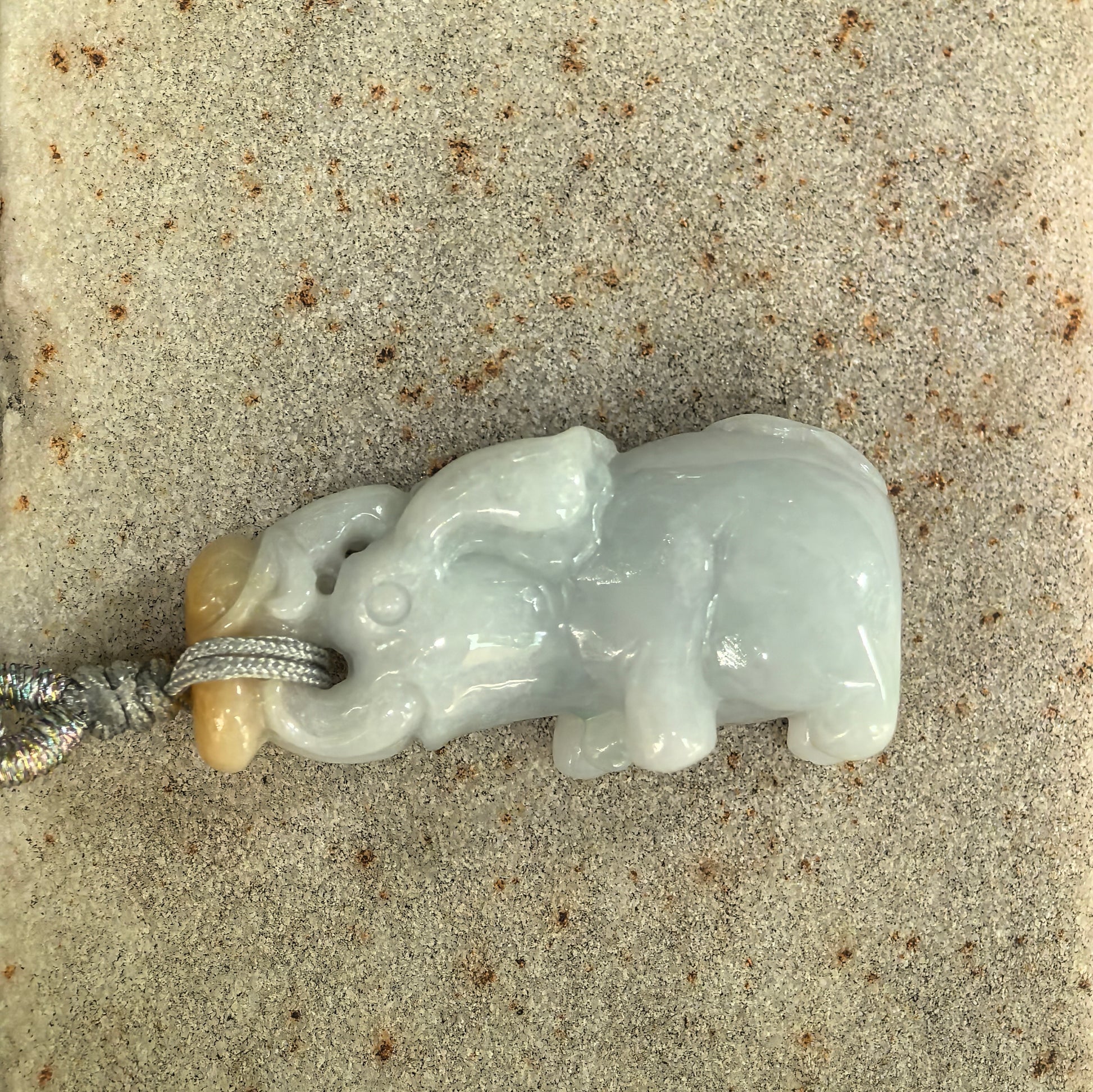 Side view of three-dimensional jadeite elephant pendant showing rounded body and raised trunk.
