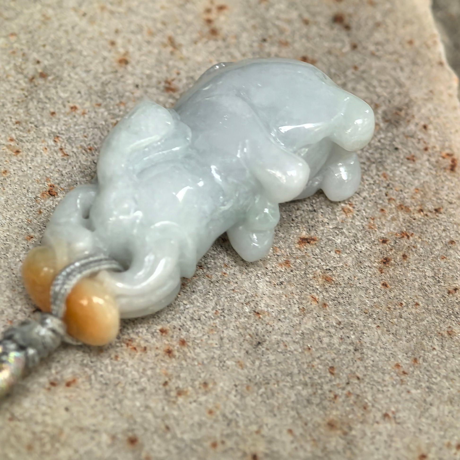 Close-up of natural jadeite elephant carving with glossy polish and soft white translucency.