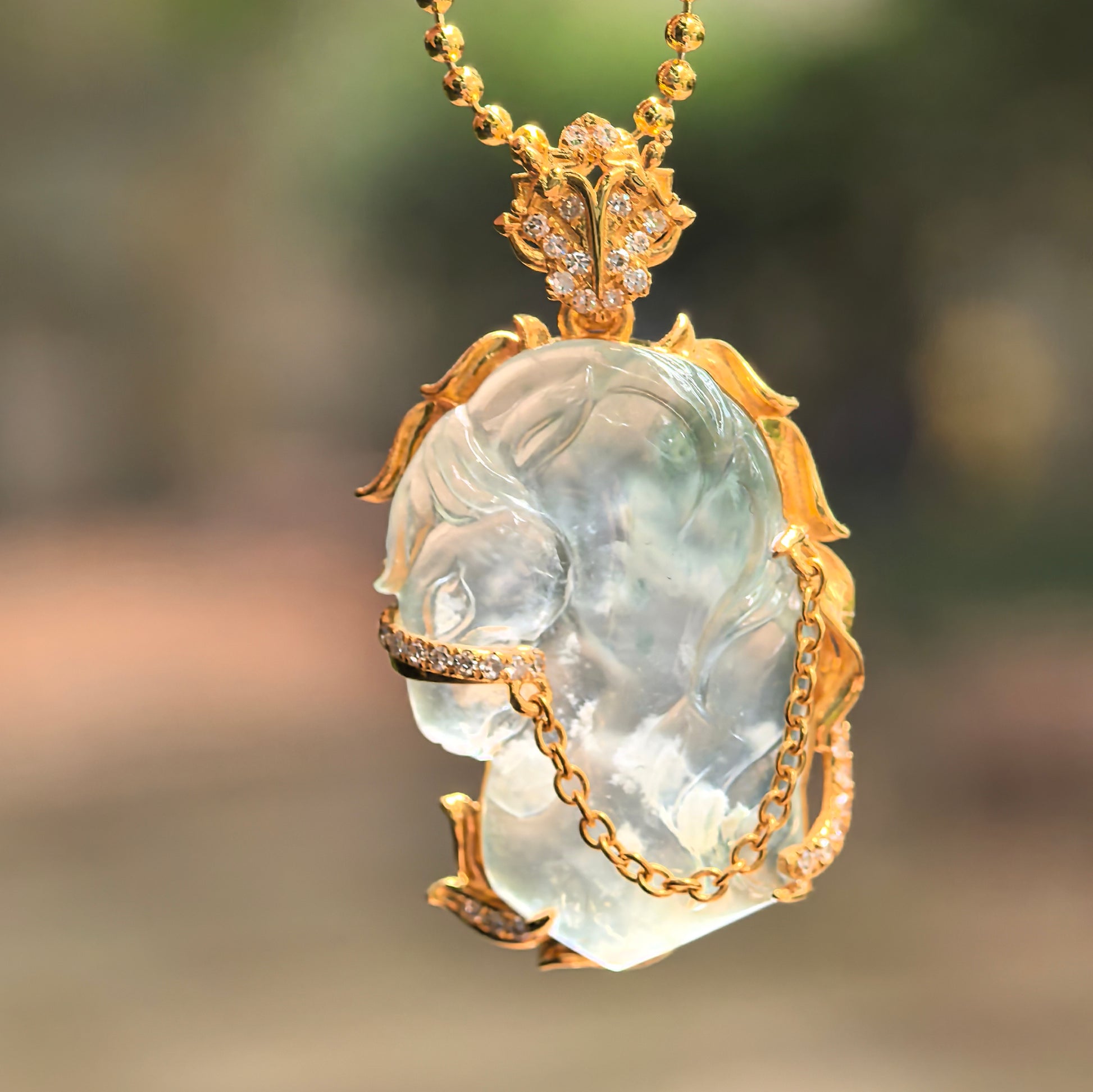 Close-up of icy translucent light green jadeite pendant highlighting horse head carving and gold mounting details.