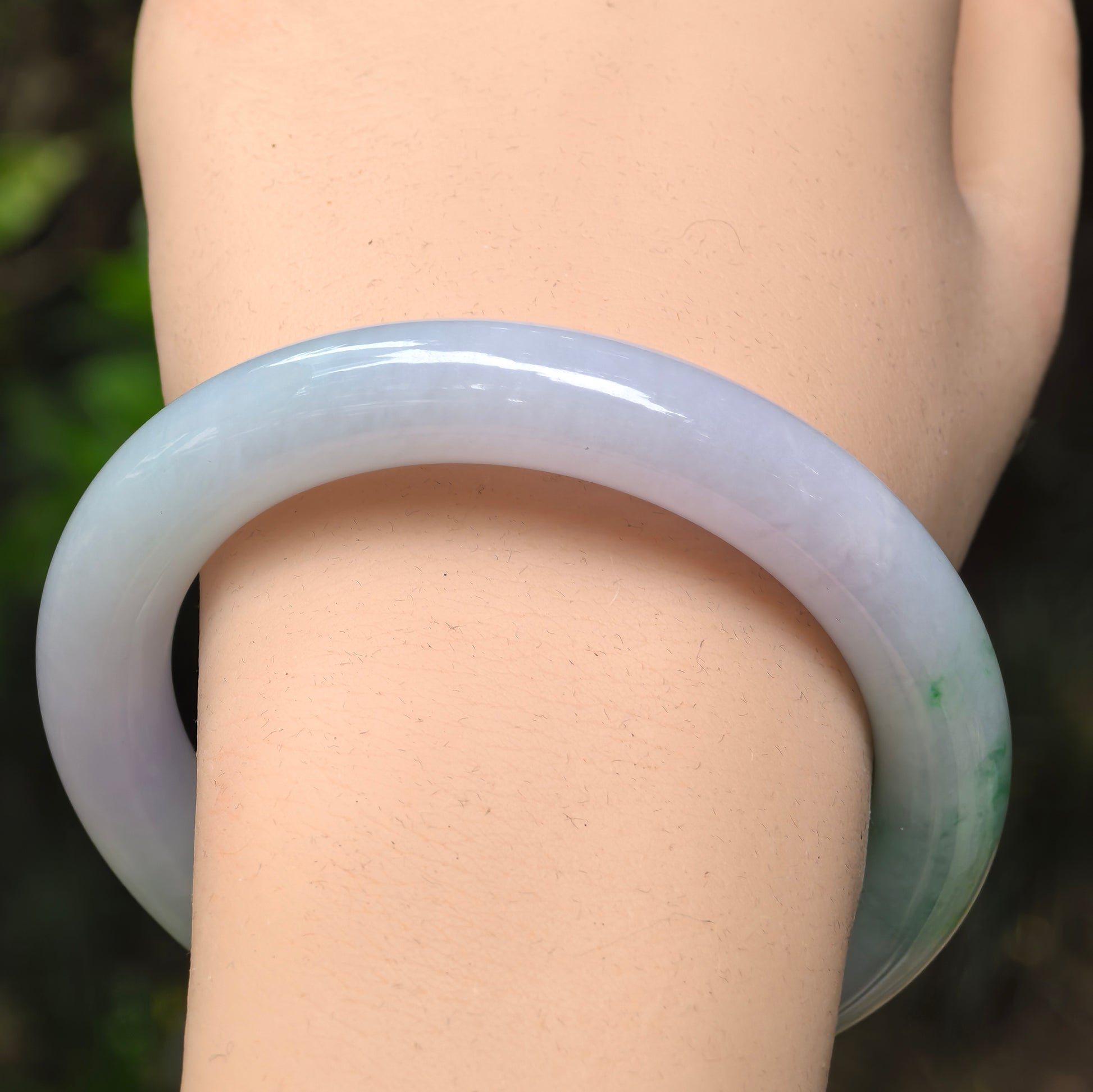 Close-up of jadeite bangle showing icy texture, pale base tone and natural green distribution.
