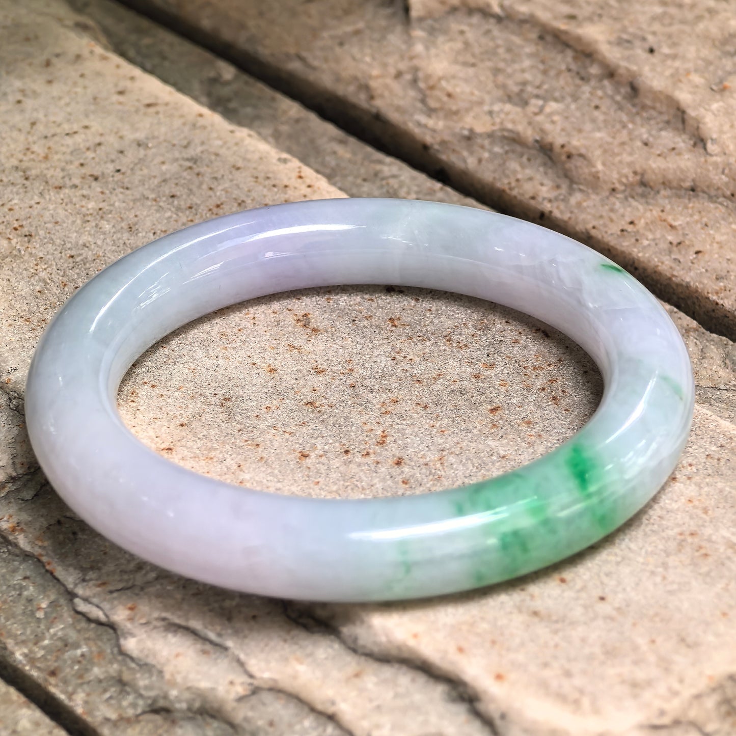 Multiple angle view of jadeite bangle emphasizing translucency, green pattern flow and surface gloss.
