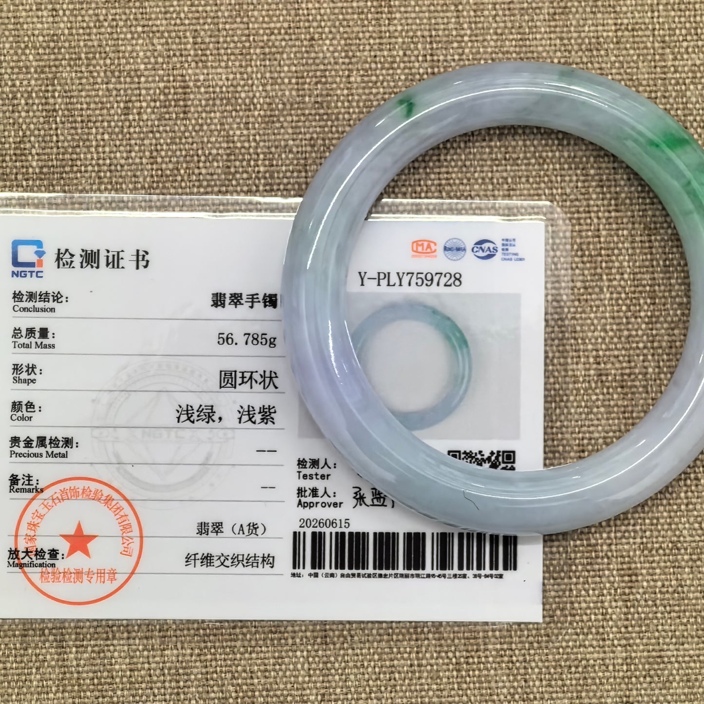 Jadeite bangle placed beside NGTC certificate showing authentication details and weight information.
