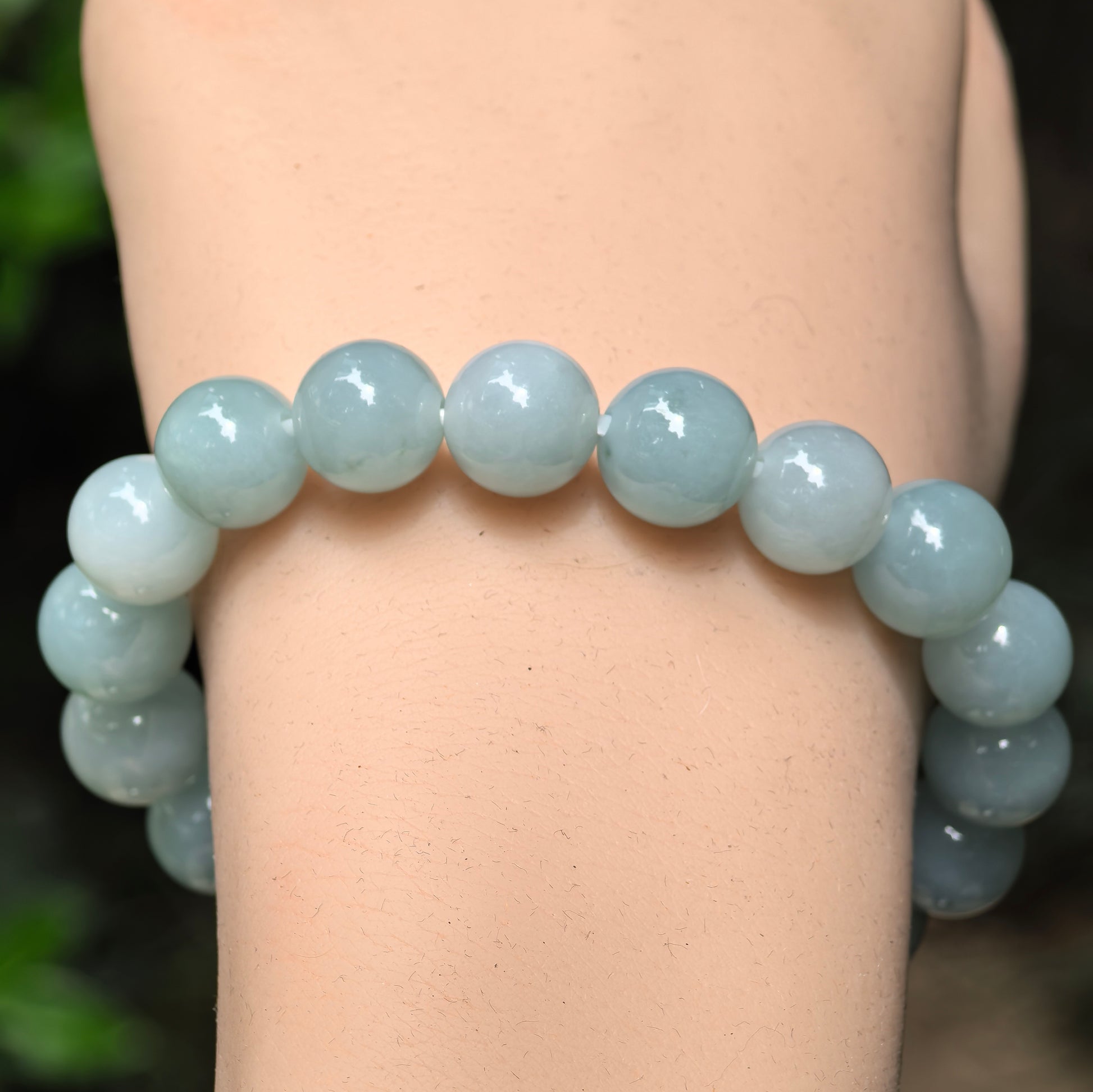 Close-up of green jadeite round beads with glossy polish and soft translucency.