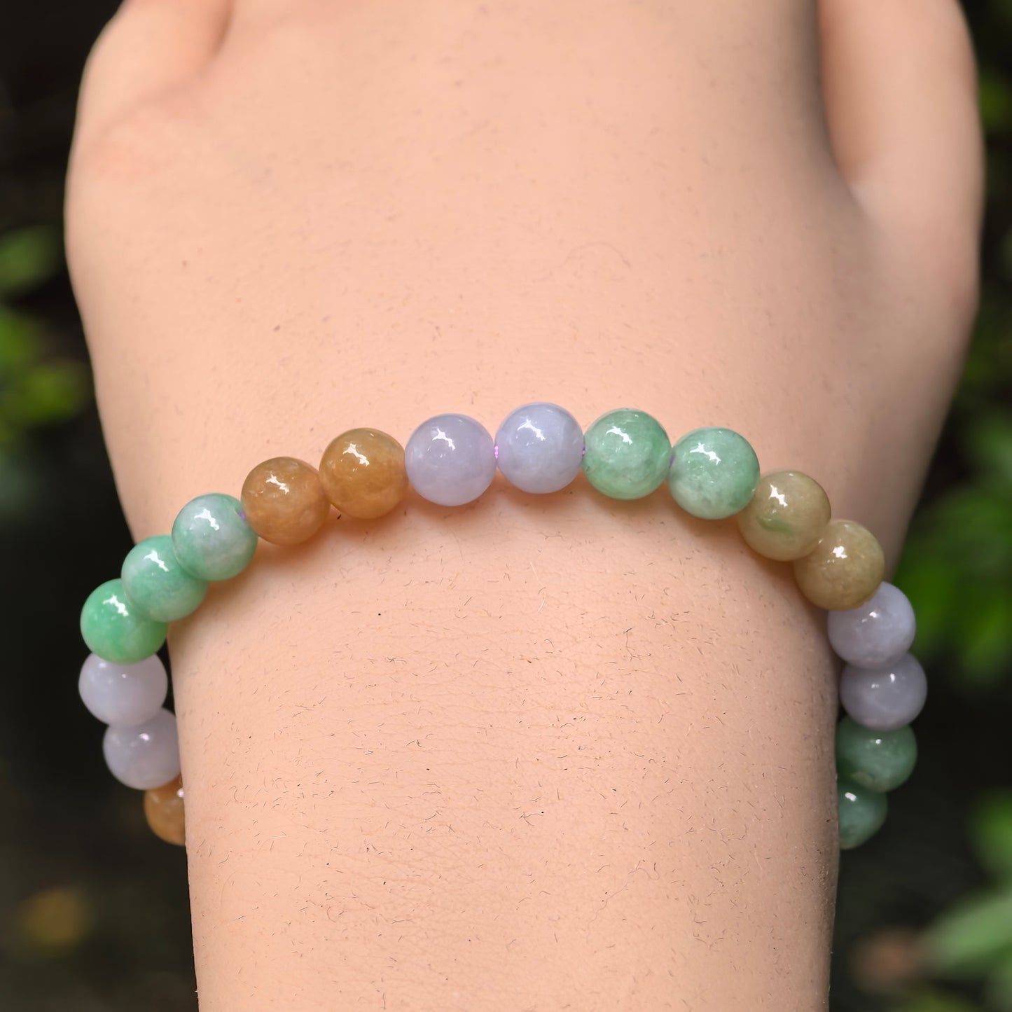 Close-up of multicolor jadeite round beads with pale green, lavender, and yellow-brown tones.