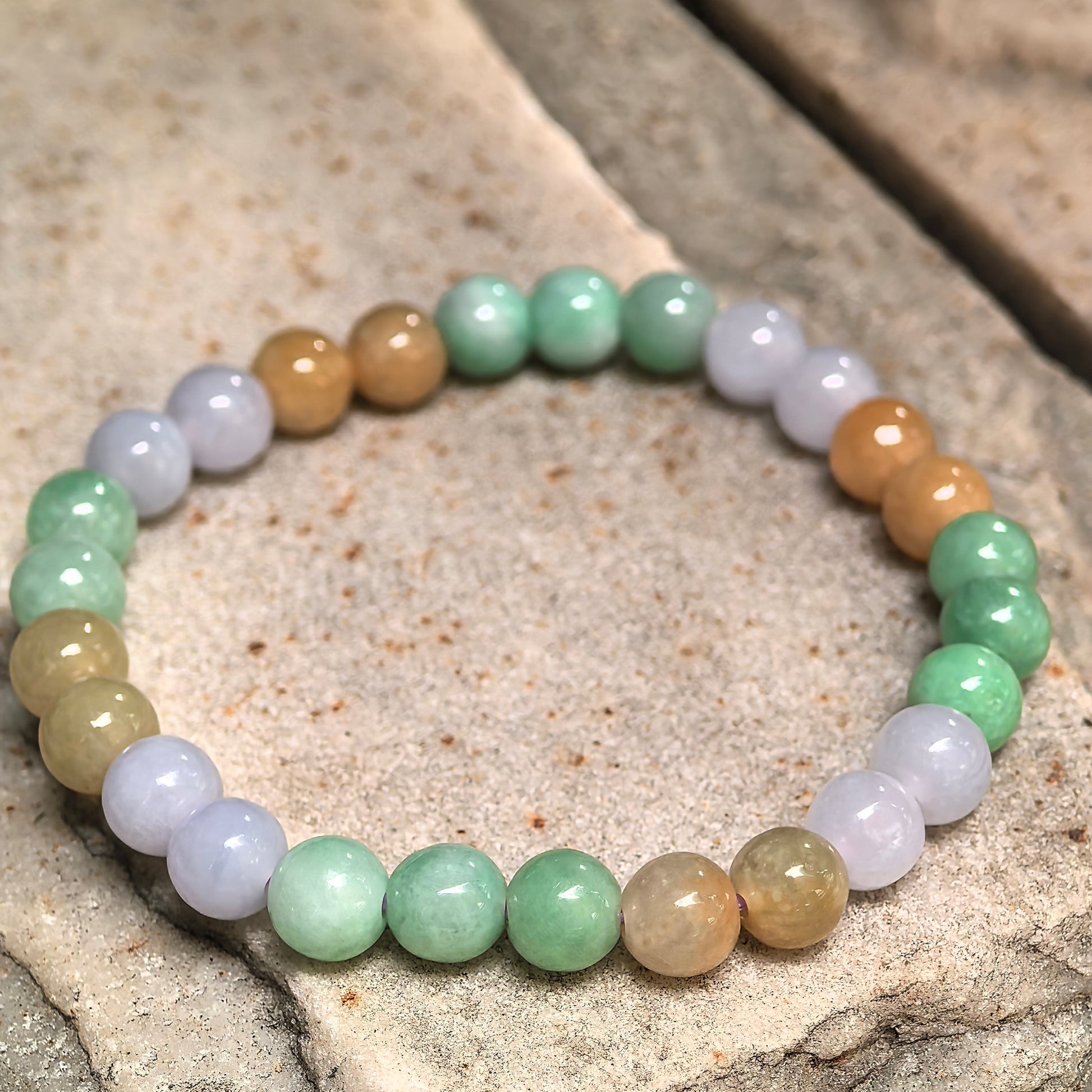 Glutinous jadeite bracelet with glossy round beads and natural color variation.