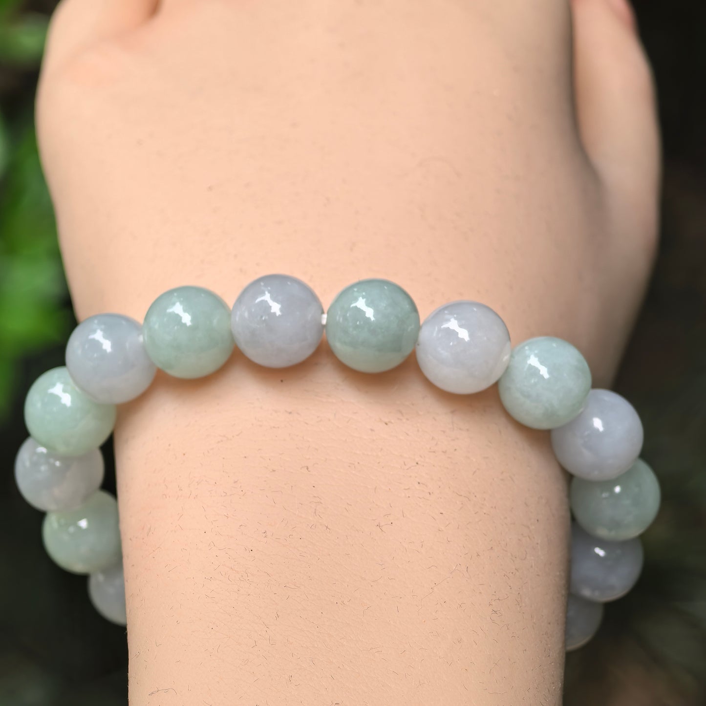 Close-up of pale green and pale lavender jadeite round beads with glossy polish.