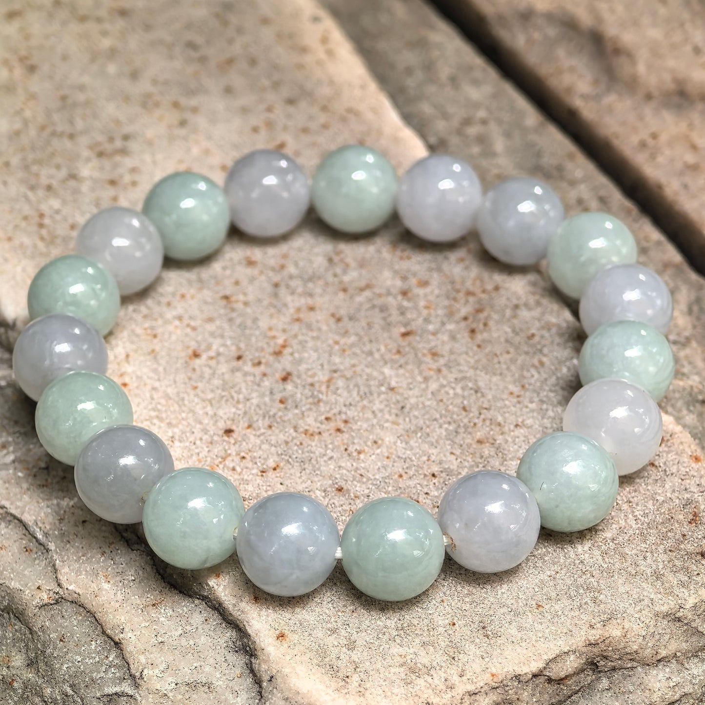 Natural jadeite bracelet showing soft pale green and lavender color variation between beads.
