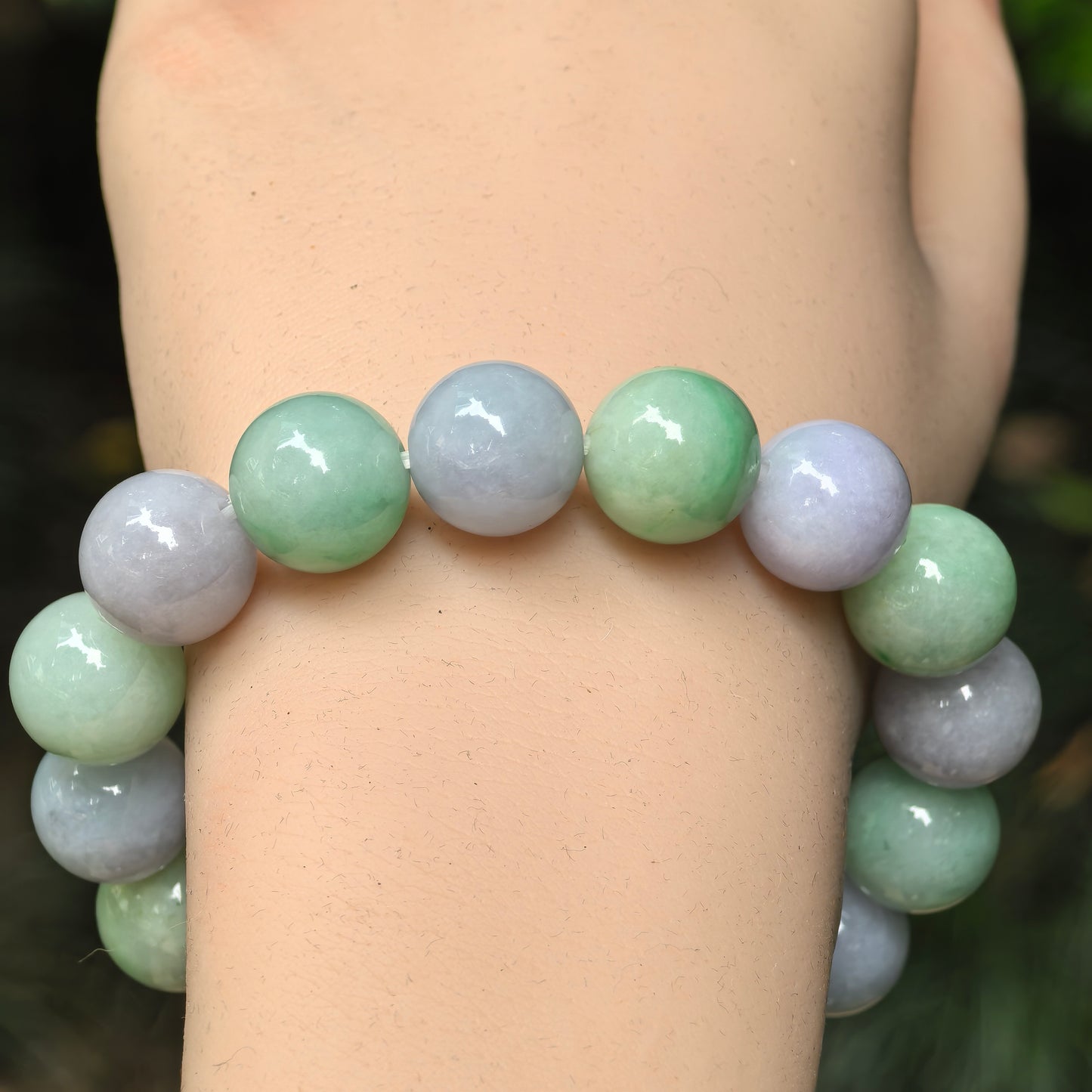 Close-up of lavender-purple and green jadeite round beads with glossy polished surface.