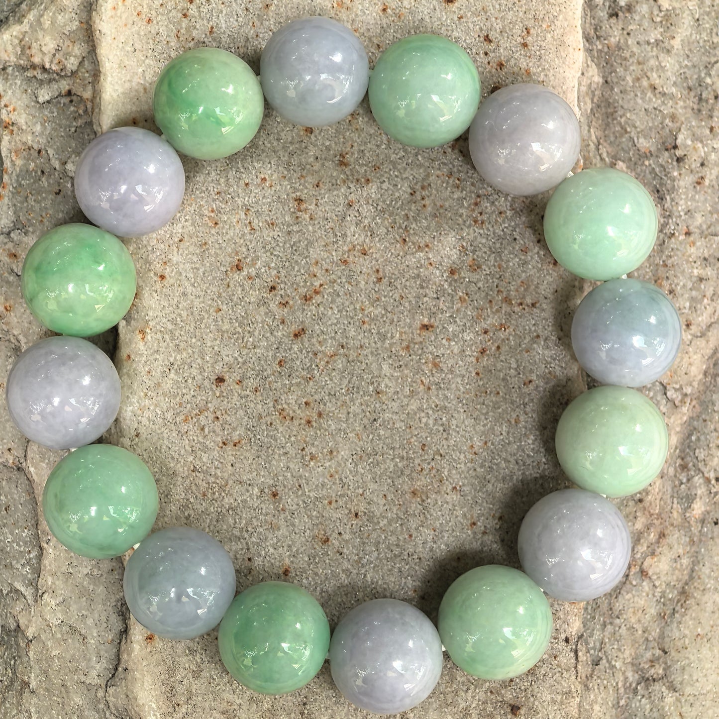 Natural jadeite bracelet with large 13mm round beads displayed on stone background.