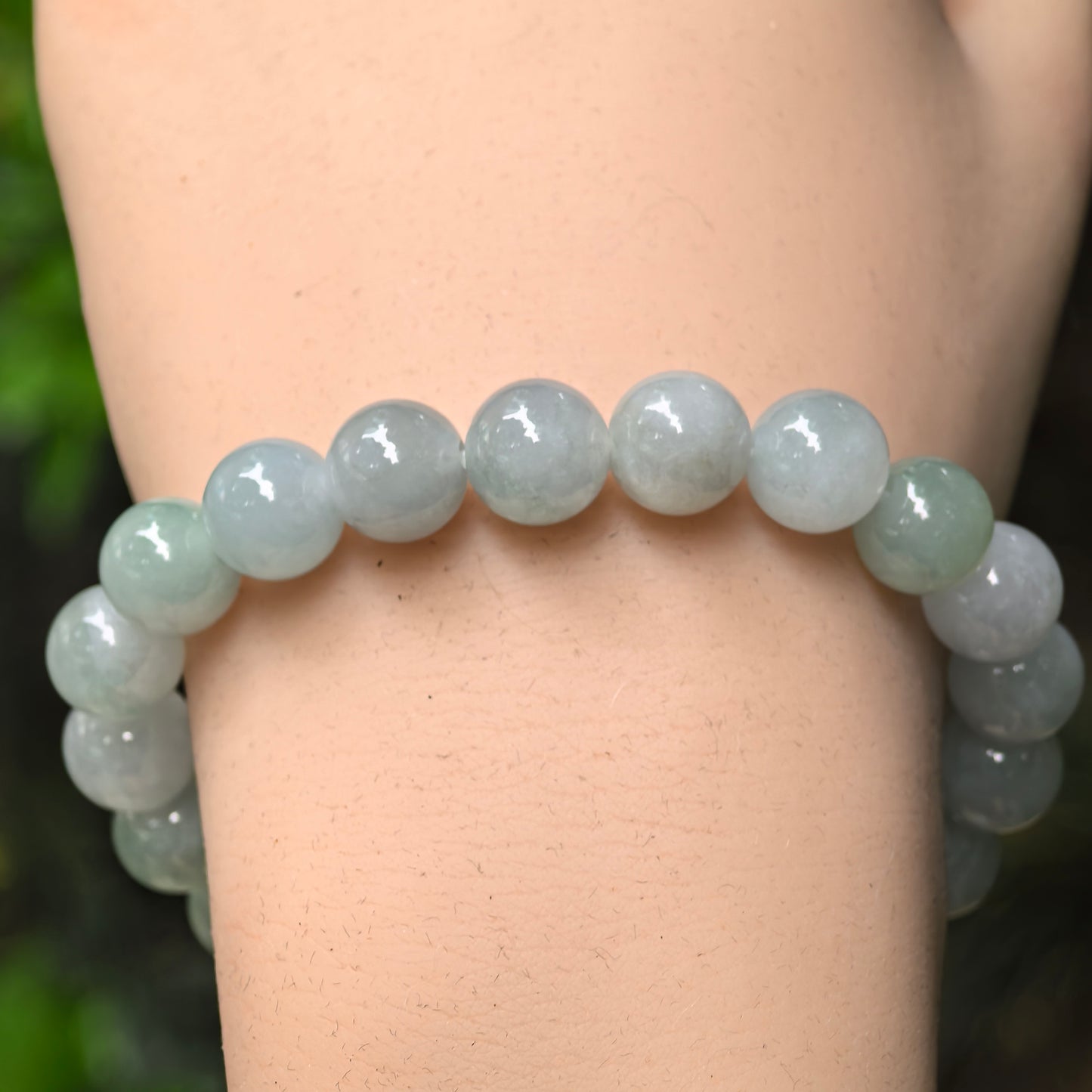 Close-up of pale green jadeite round beads with soft translucency and glossy polish.