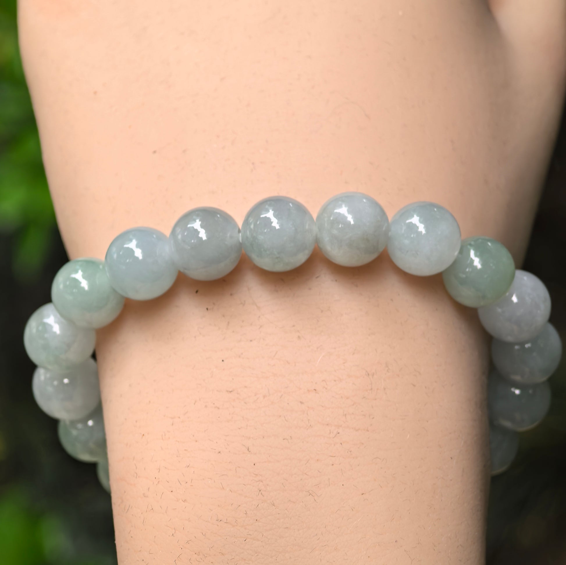 Close-up of pale green jadeite round beads with soft translucency and glossy polish.