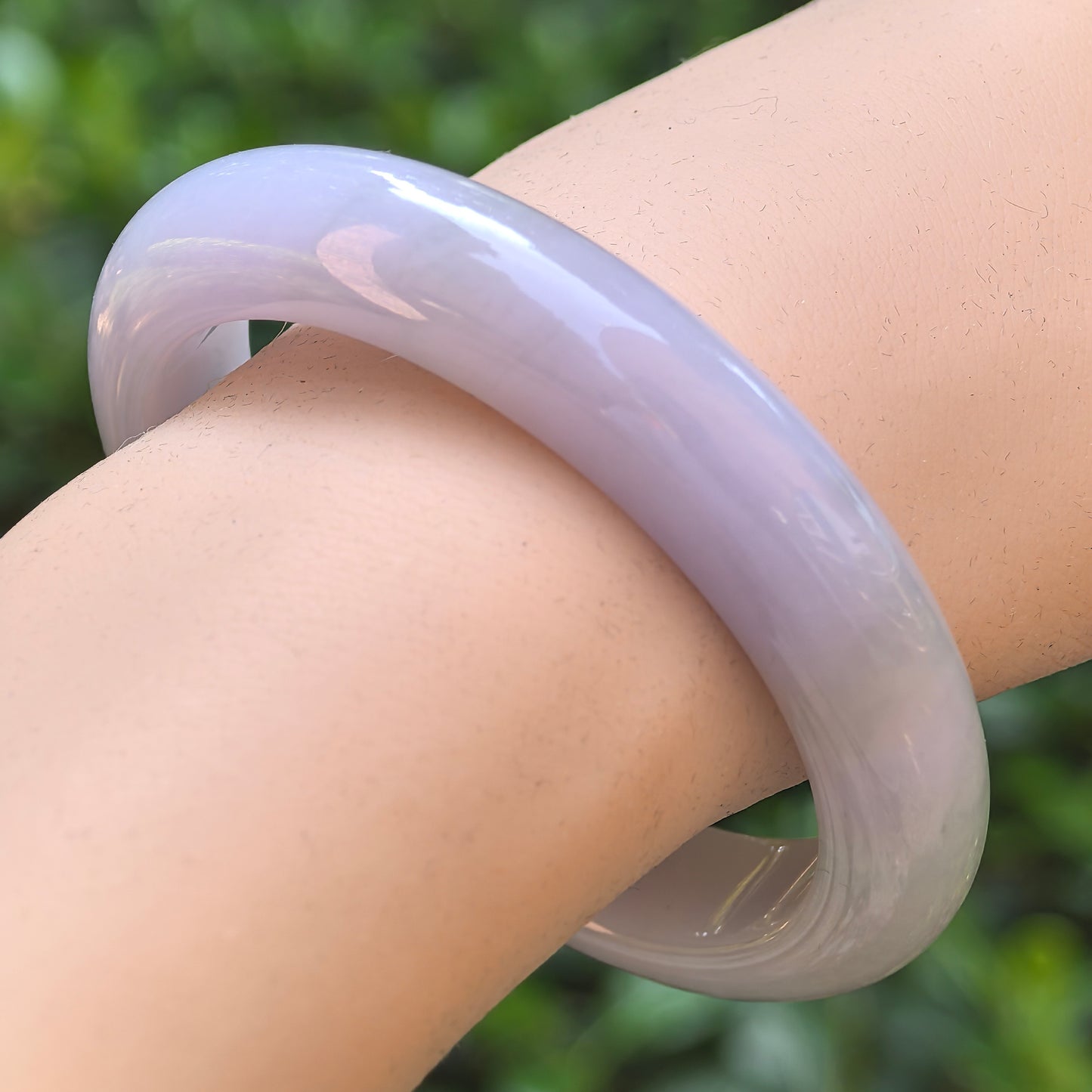 Natural Grade-A glutinous light lavender D-shape jadeite bangle worn on the wrist.