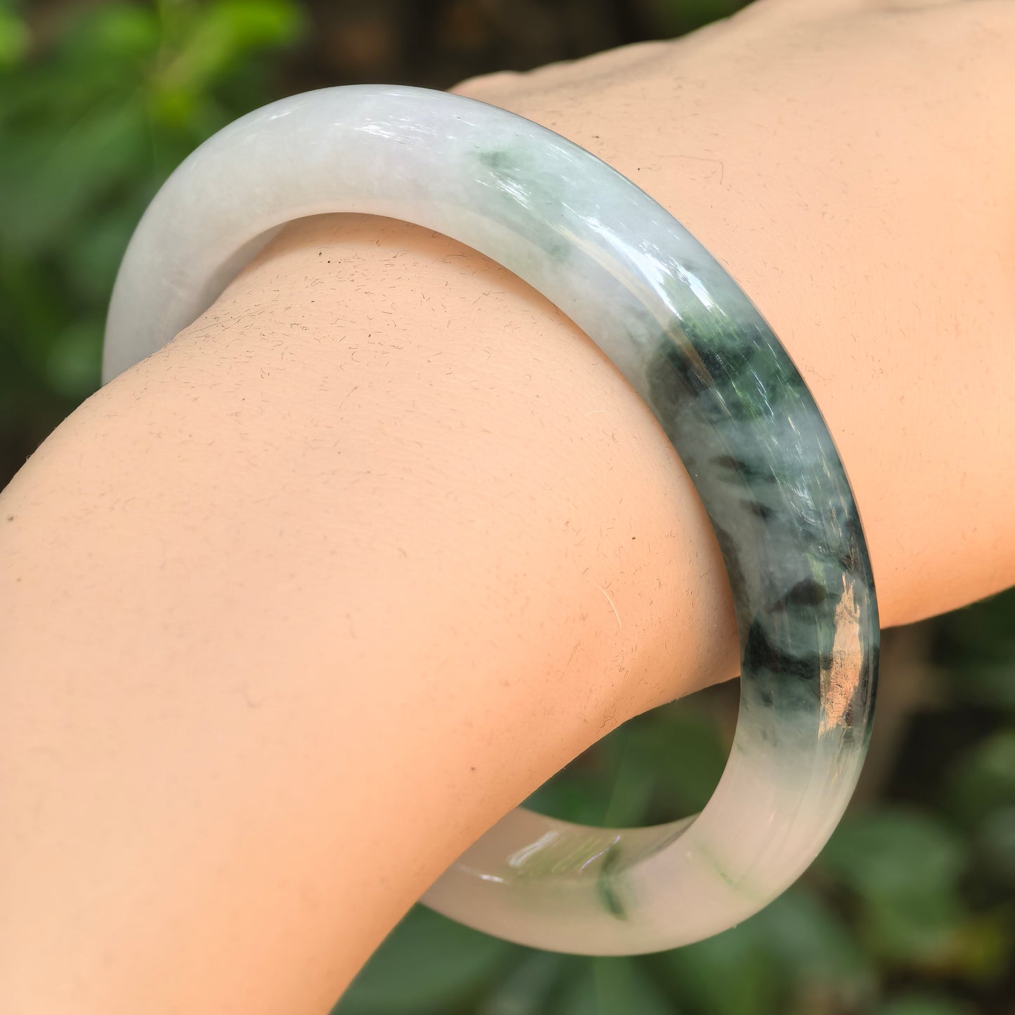 Natural Grade-A glutinous green floating flower D-shape jadeite bangle worn on the wrist.
