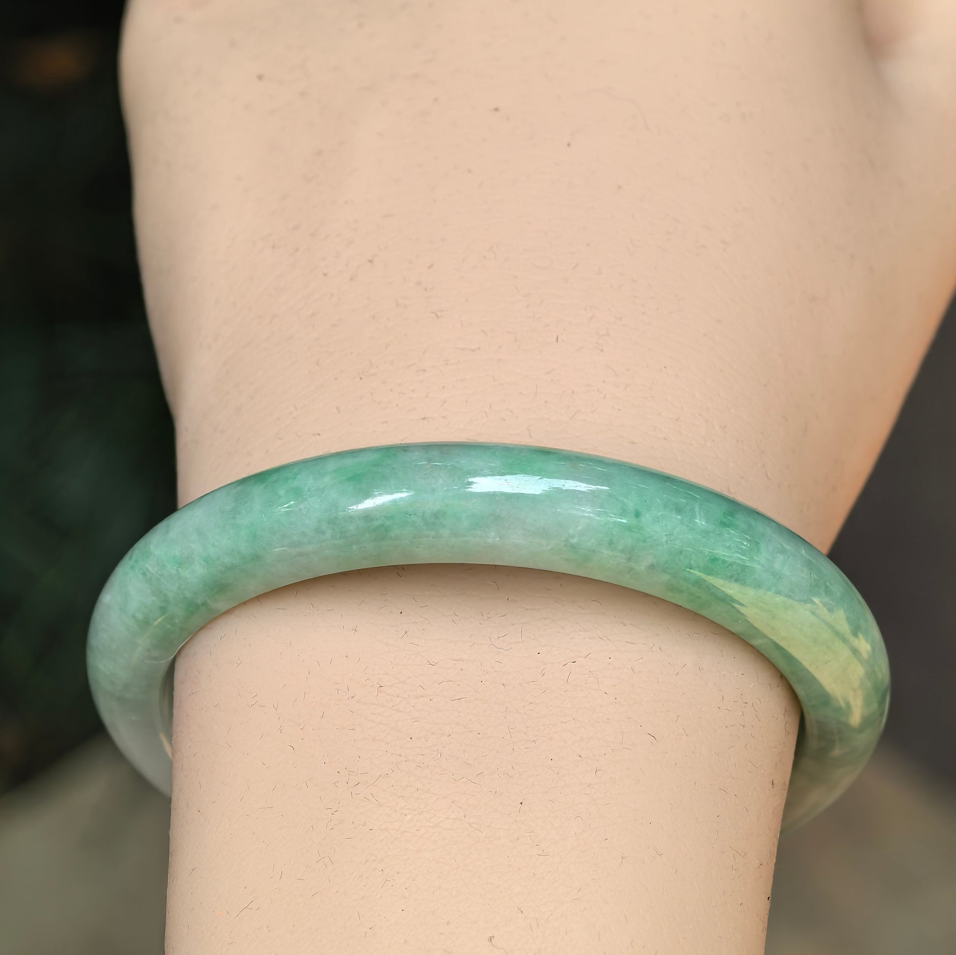 Close-up of a light green jadeite bangle showing smooth polished luster.
