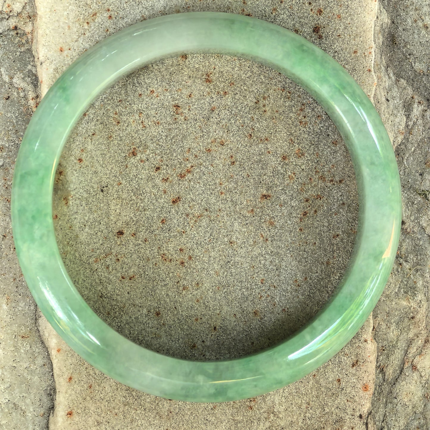 Top view of a slim green jadeite bangle with classic circular form.
