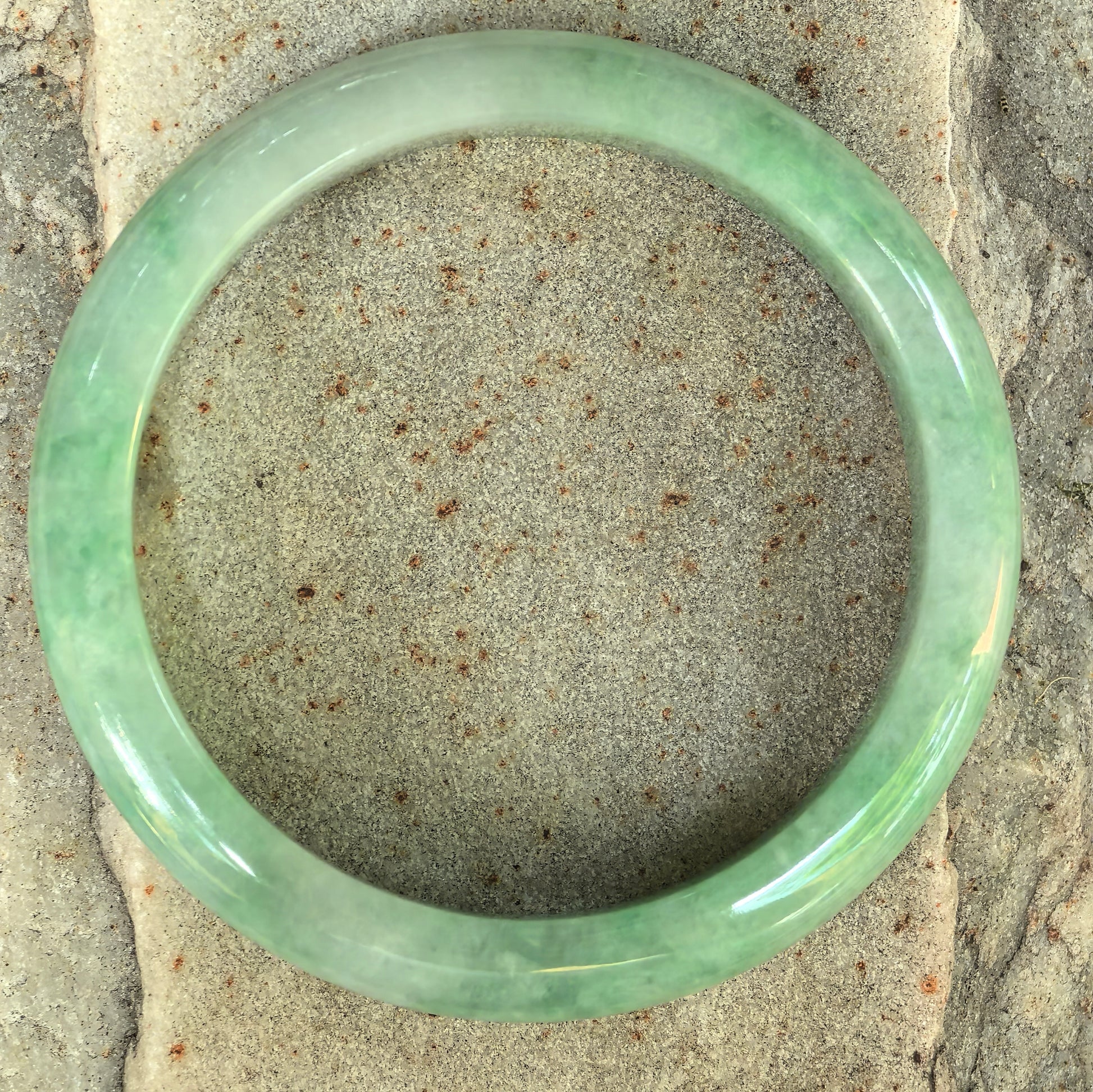 Top view of a slim green jadeite bangle with classic circular form.
