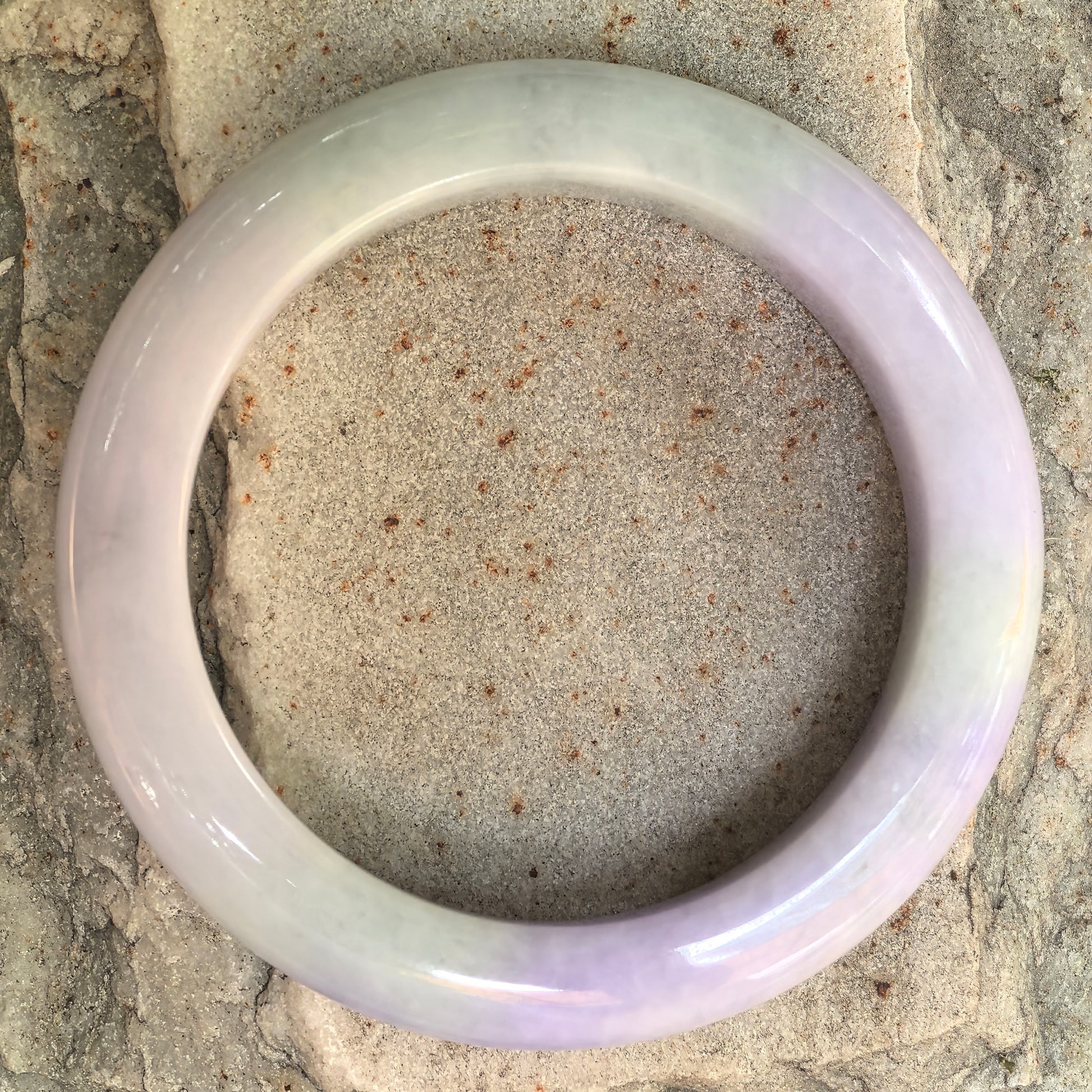 Top view of a purple green jadeite bangle with classic circular form.
