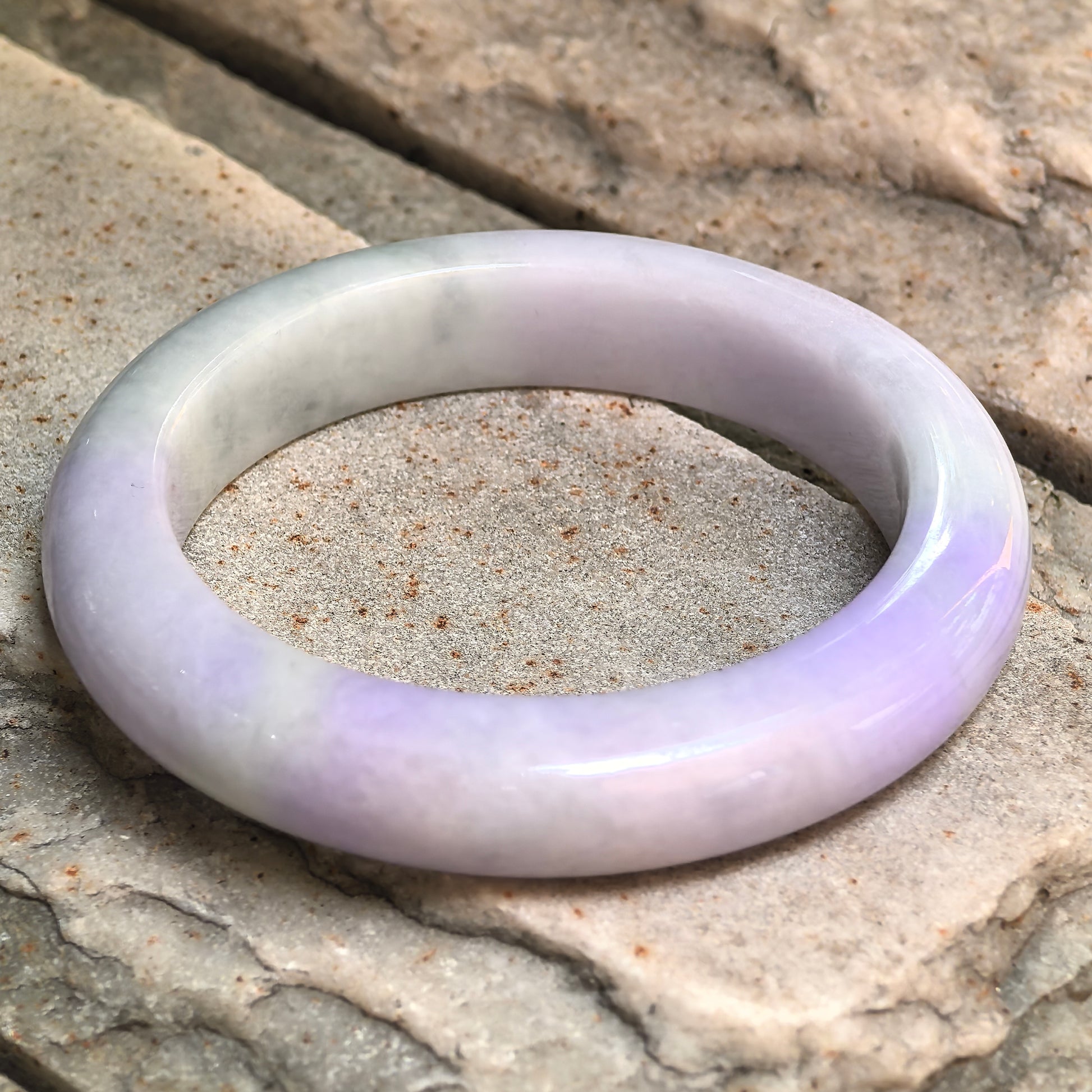 Angled view of a D-shape jadeite bangle with soft glutinous texture.
