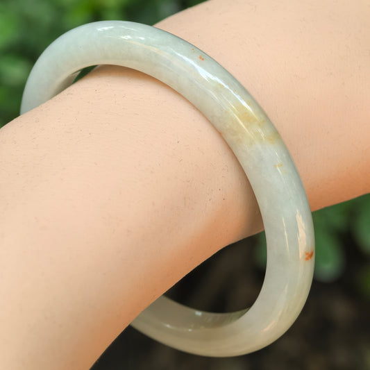 Natural Grade-A glutinous white scattered-gold D-shape jadeite bangle worn on the wrist.
