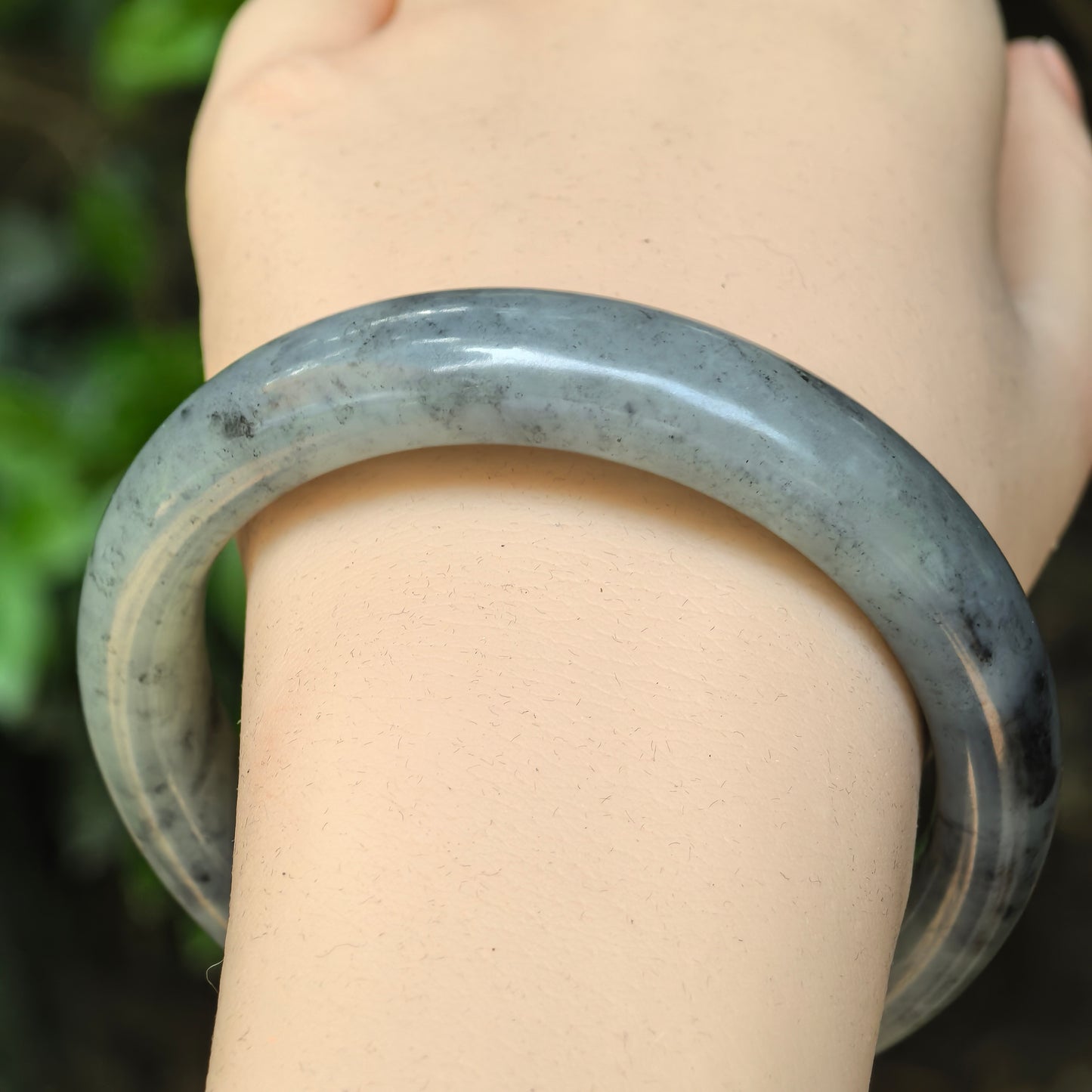 Close-up of a grey-black Hetian jade bangle with smooth polished luster.
