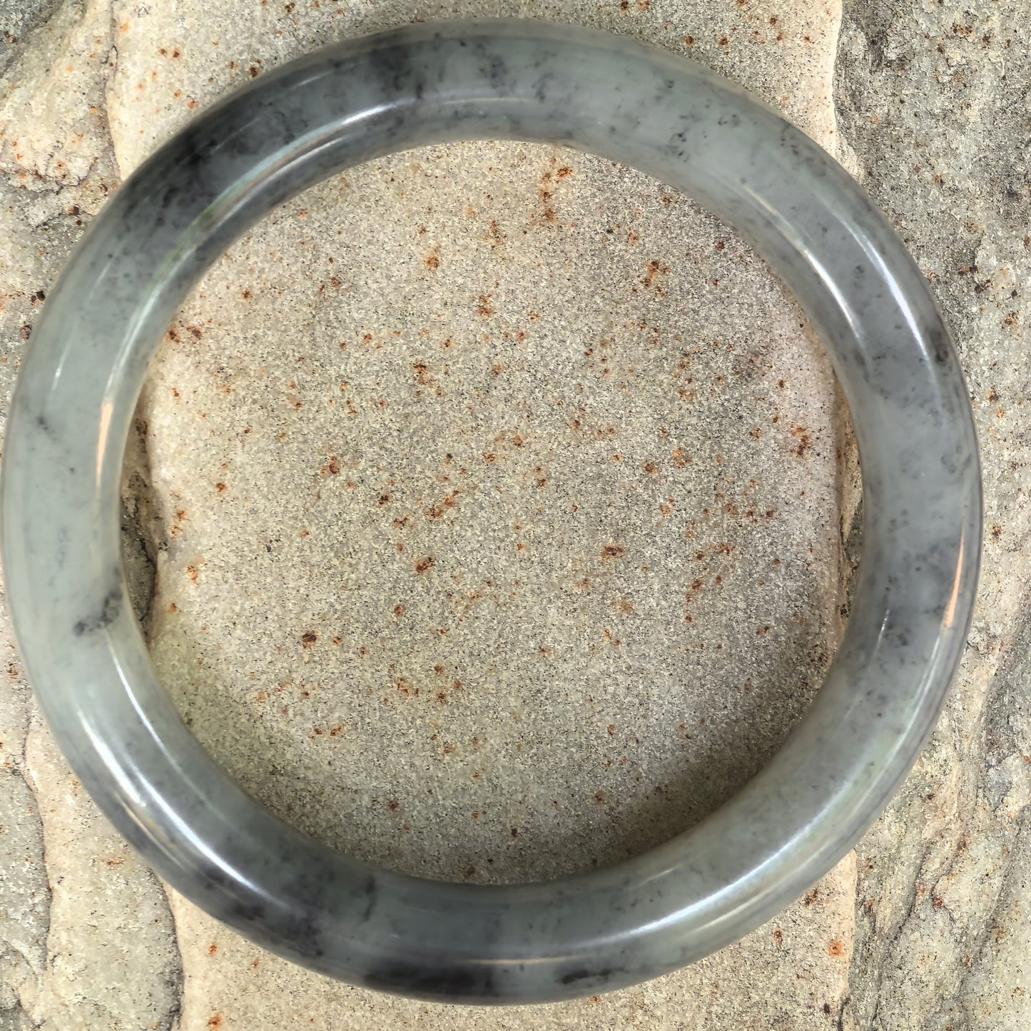 Top view of an ink-wash Hetian jade bangle showing natural dark patterns.
