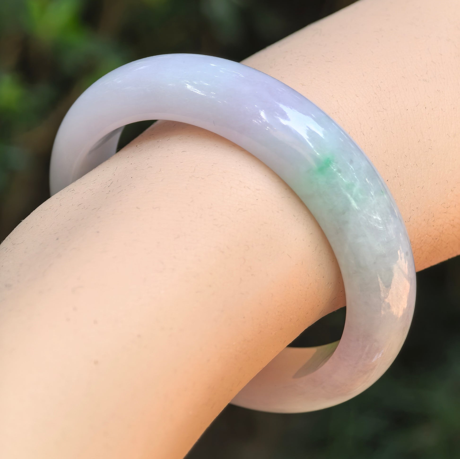 Natural Grade-A glutinous purple green oval jadeite bangle worn on the wrist.
